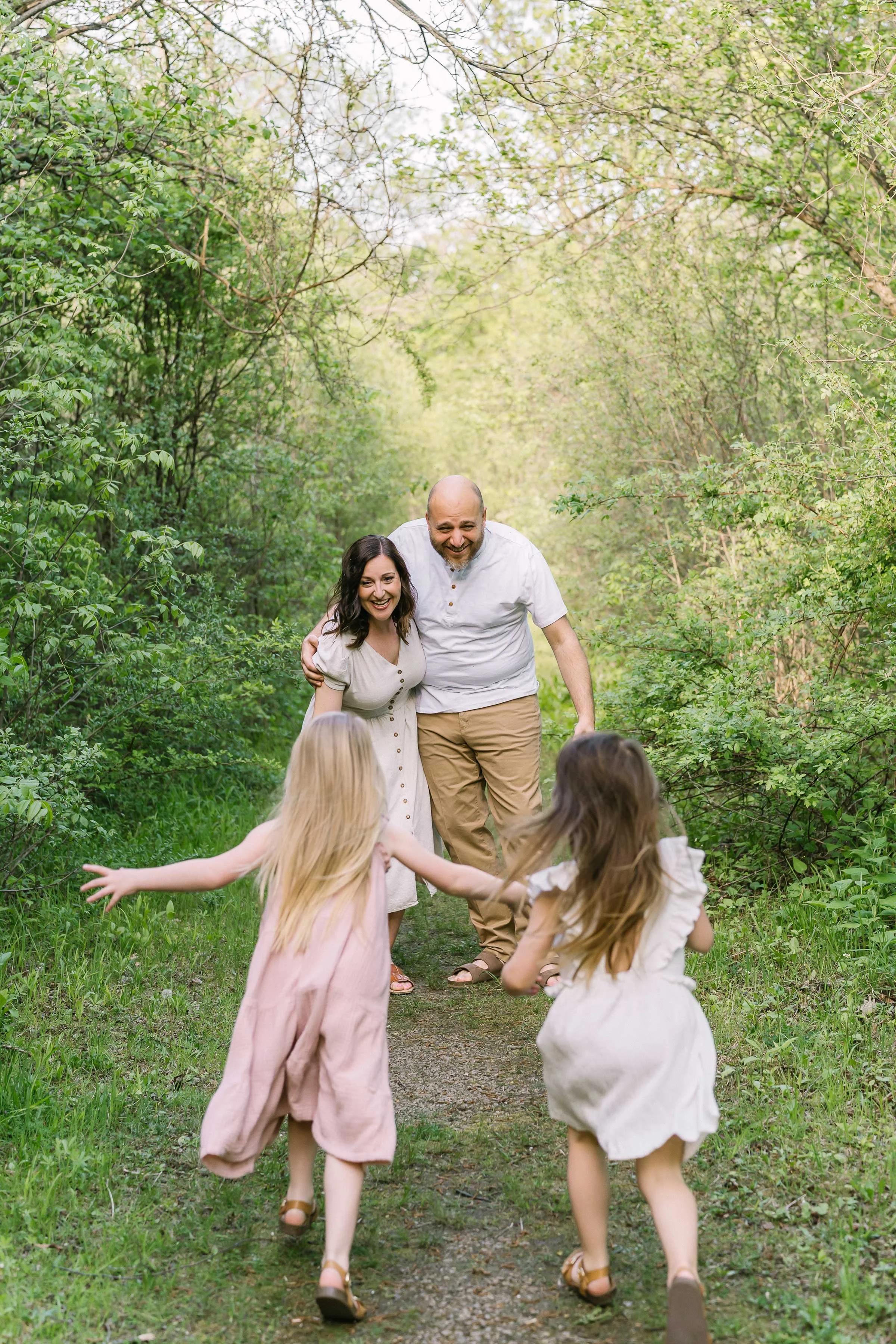 Parents laughing with their daughters on a Niagara wooded trail family photo session