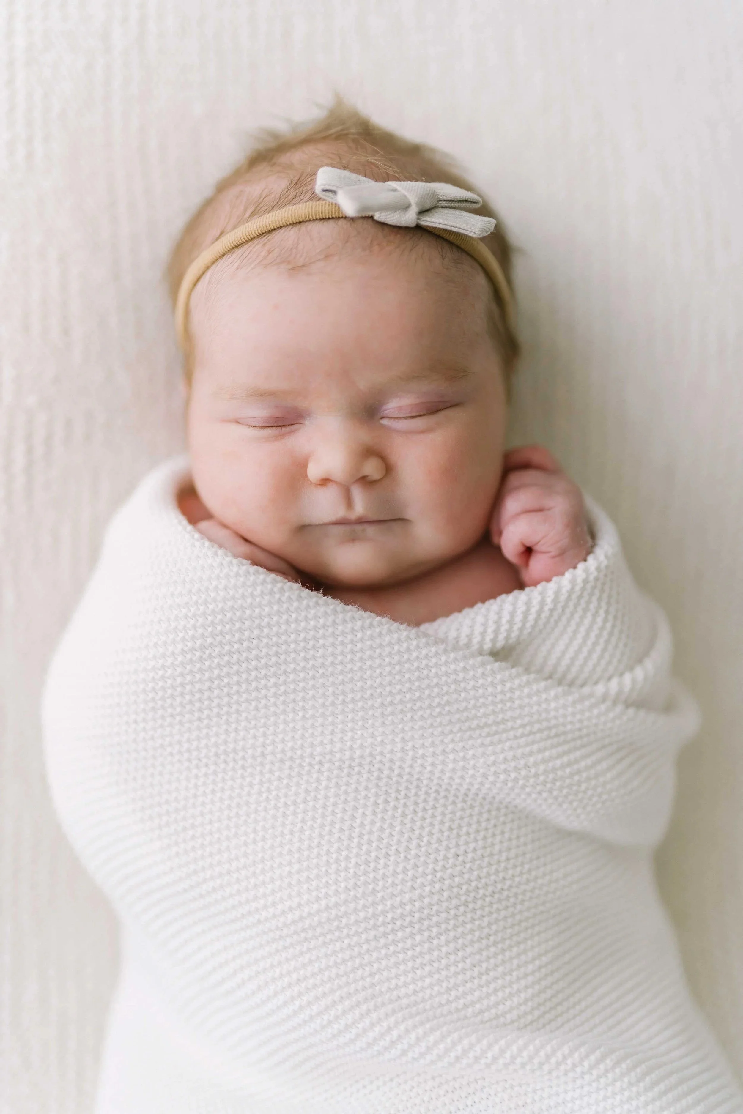 Sleeping newborn baby wrapped in white knit wrap at Grimsby photography studio