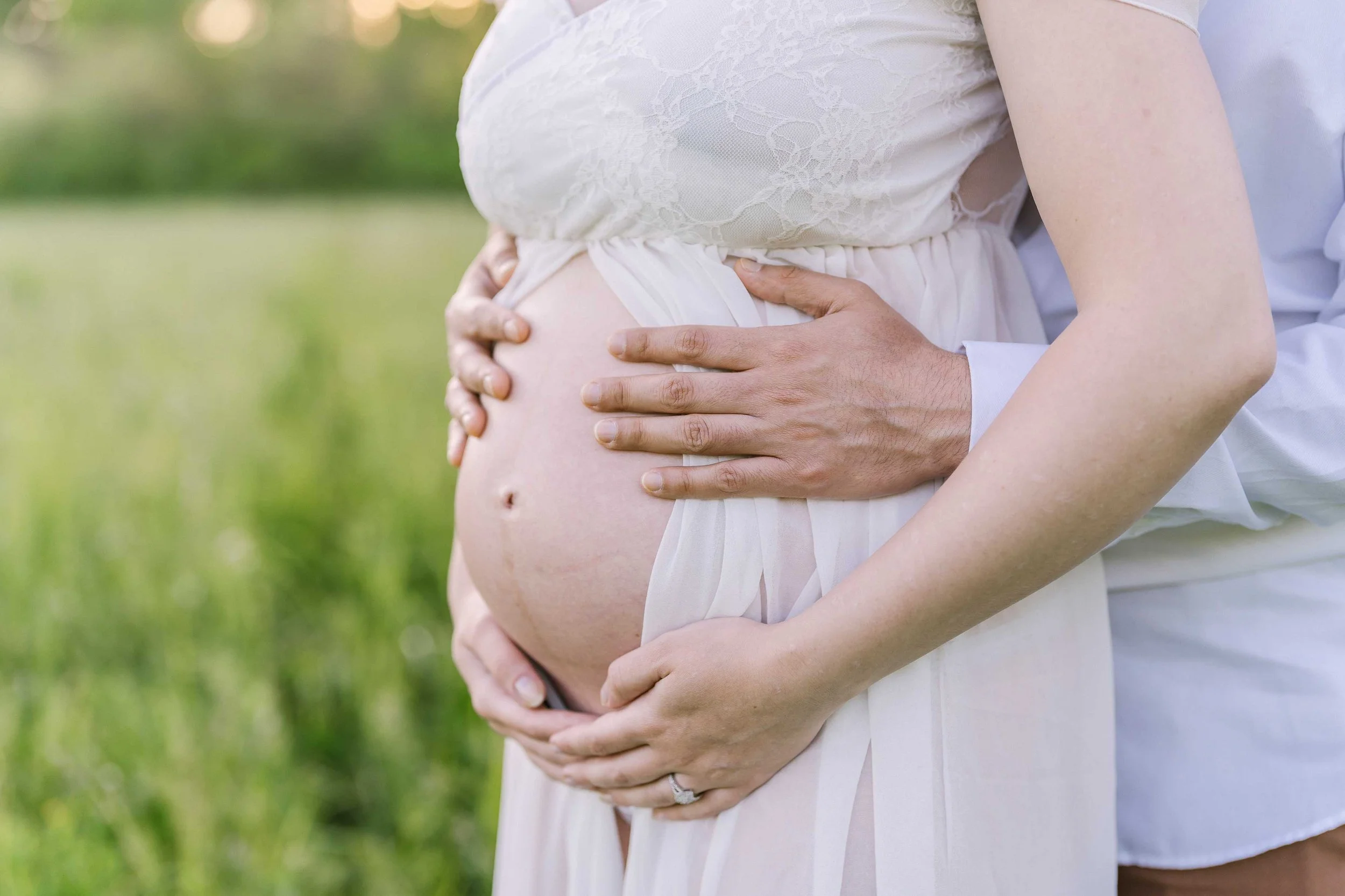 Expectant parents holding hands on a field during maternity photography session
