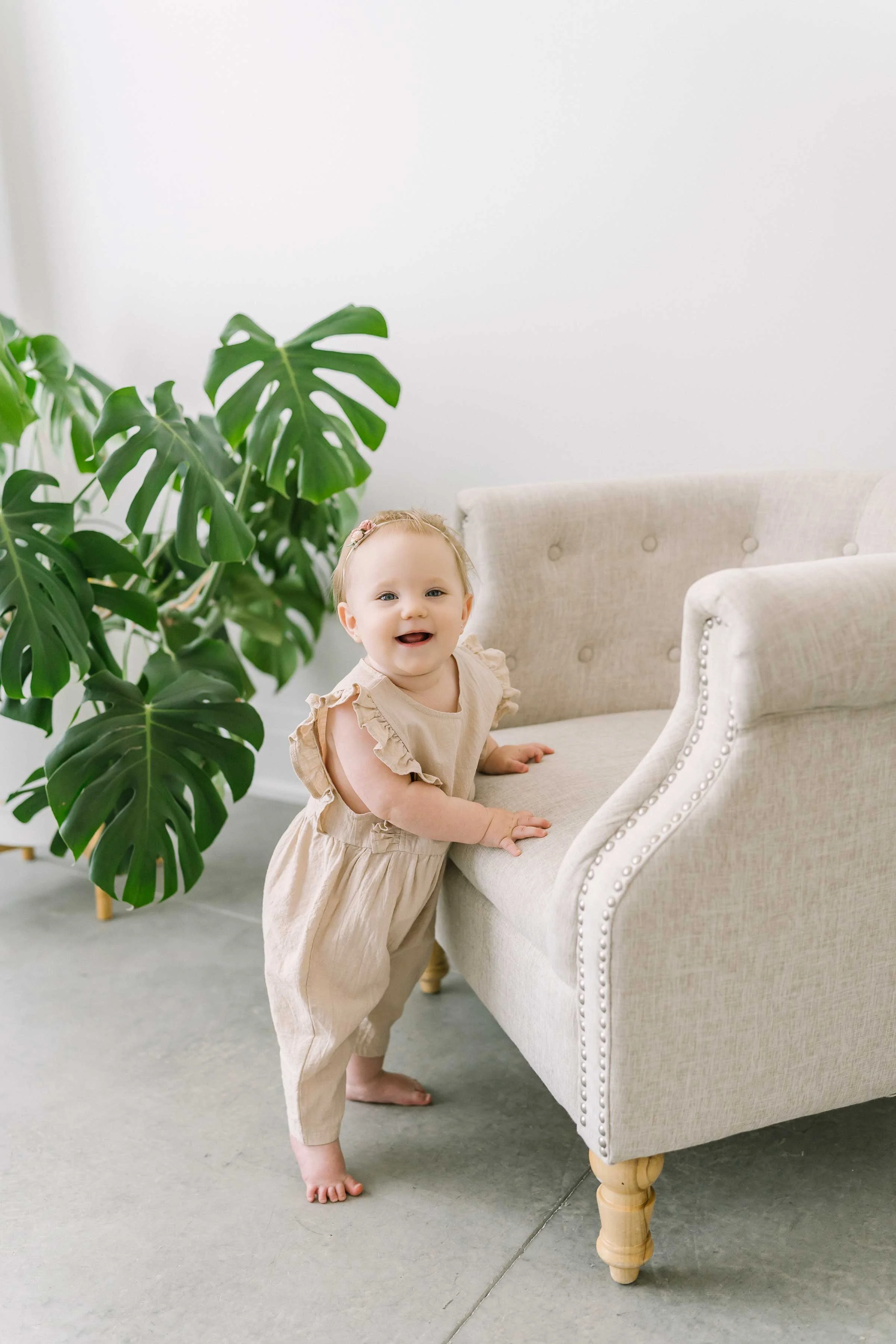 Baby girl pulling up to stand at a studio chair during her first year photos in Grimsby