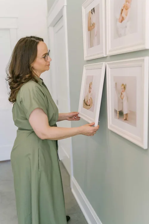 newborn photographer in niagara hanging family pictures on a wall