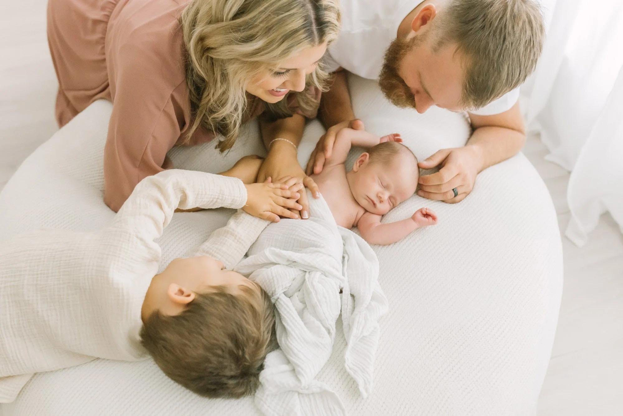 newborn photography in Hamilton Ontario​ with family surrounding newborn on a beanbag