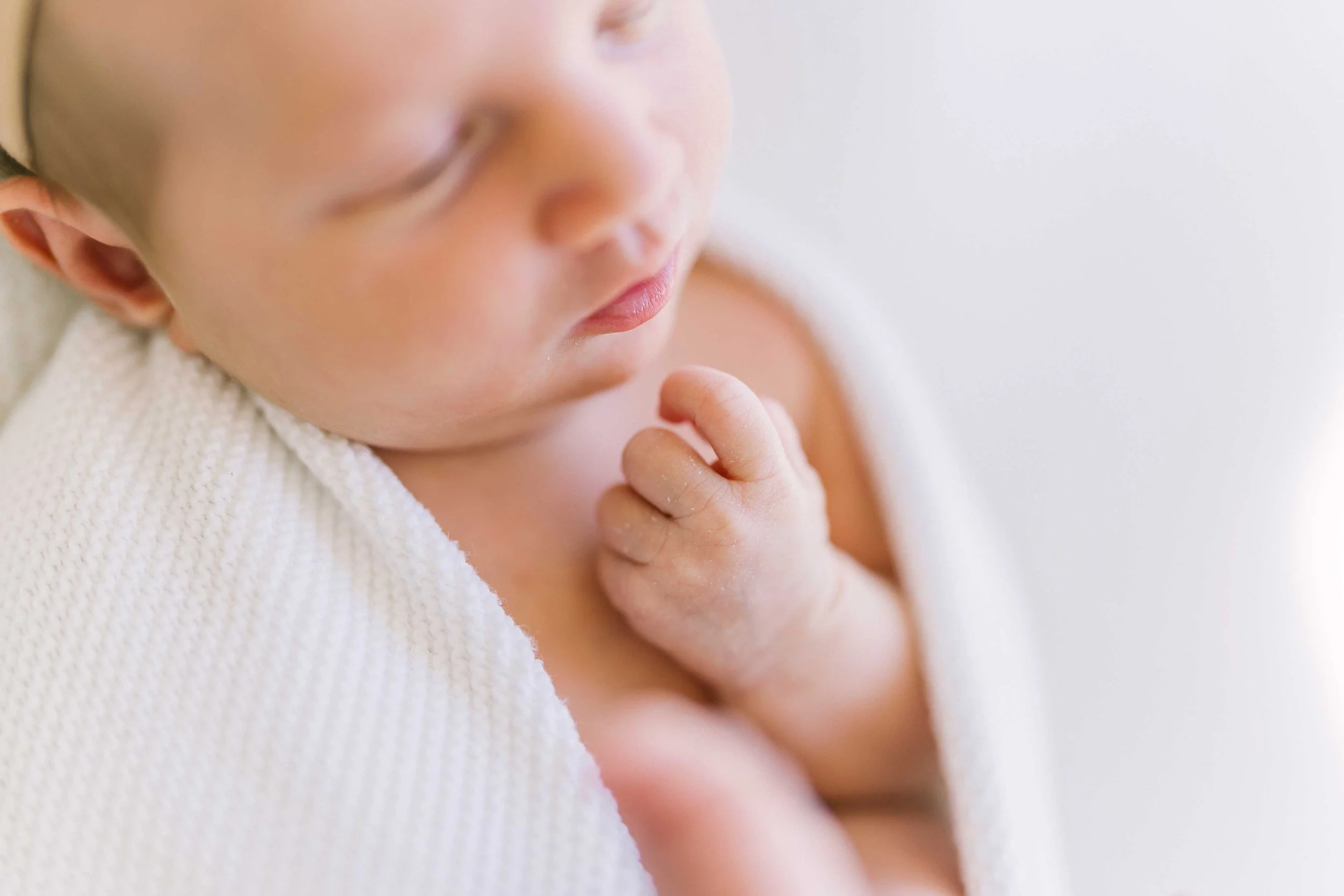 Close-up of a sleeping newborn's tiny hand resting under her chin in our Grimsby studio