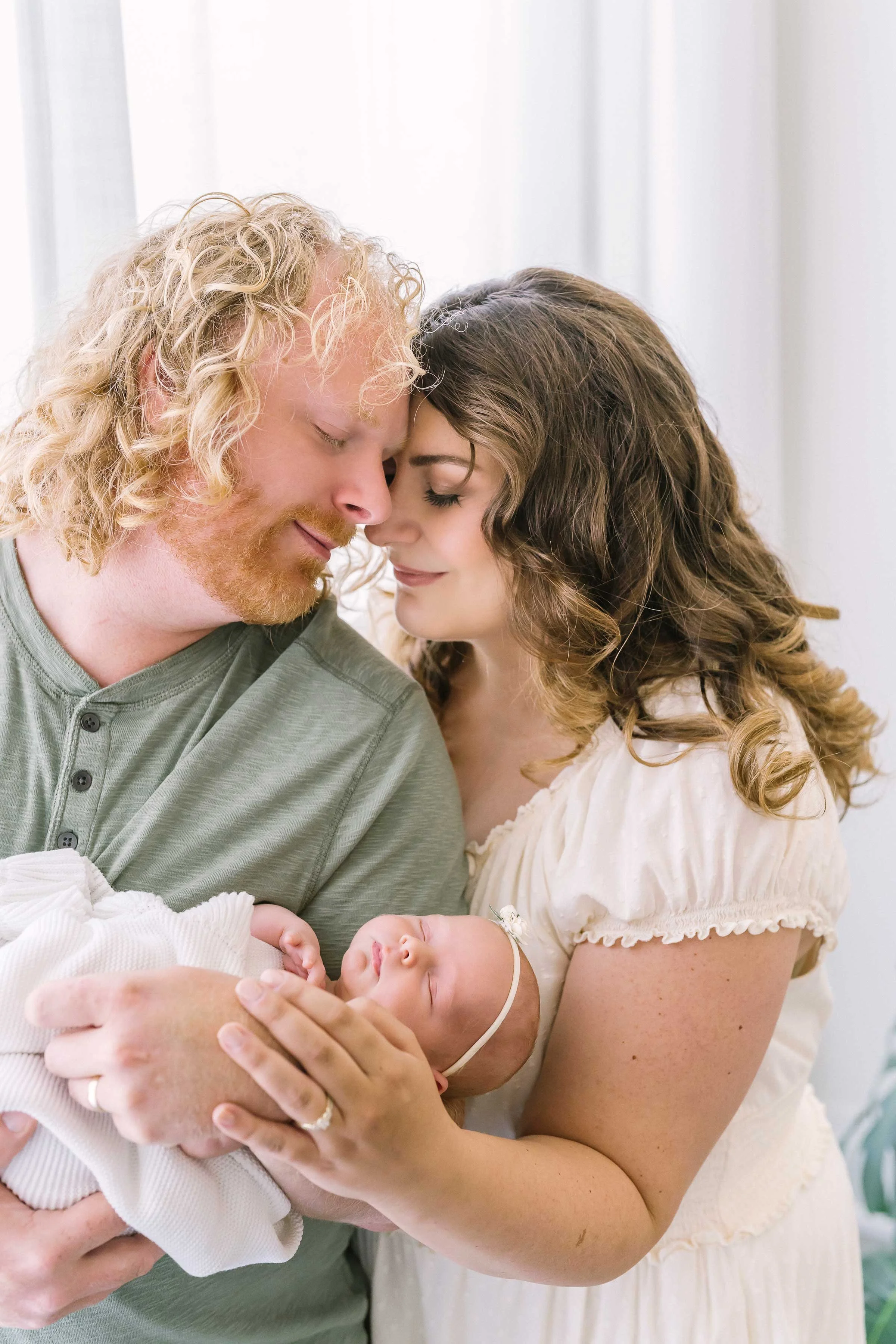 Lupia parents cuddling their newborn baby girl during a family photo session