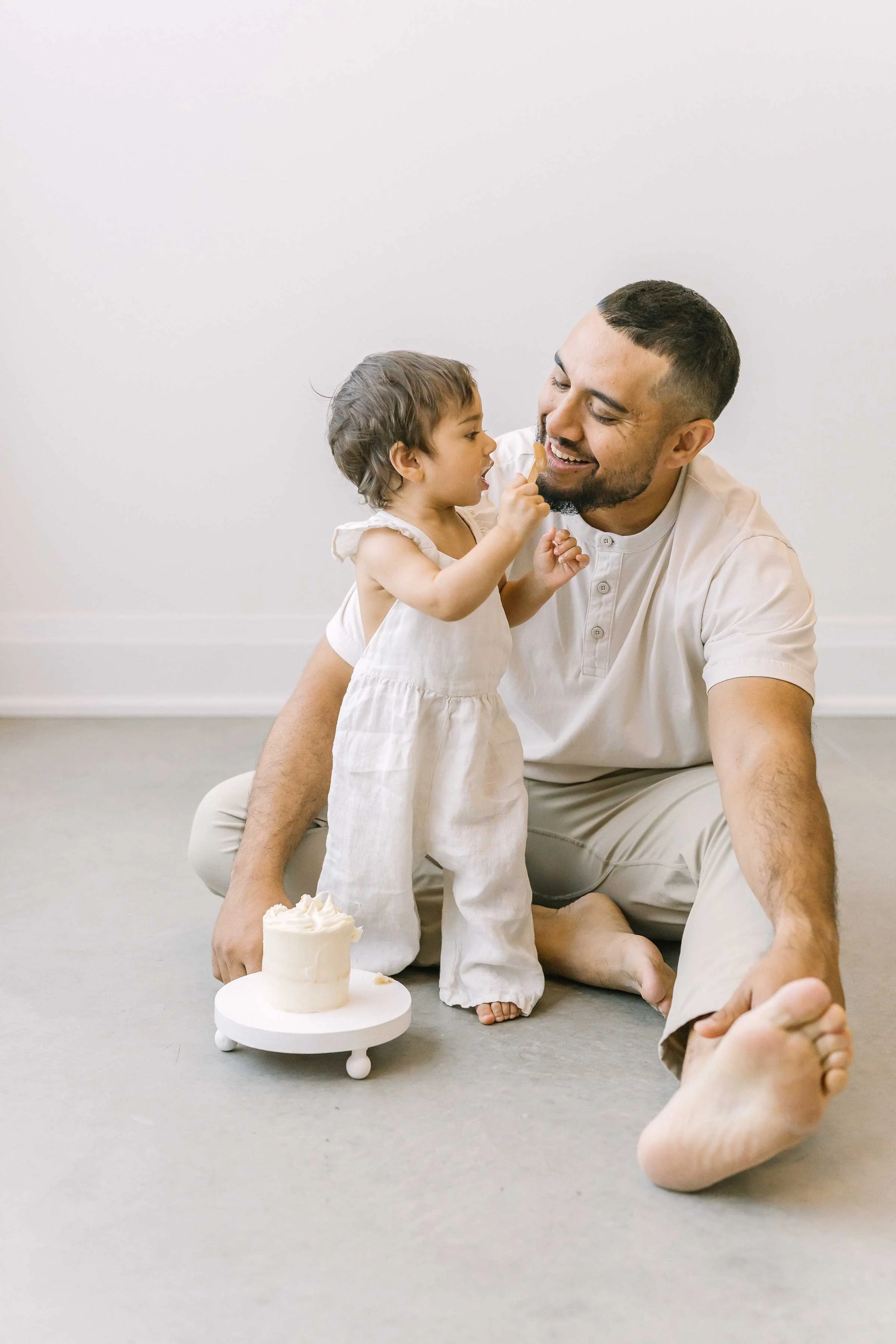 Dad and toddler sharing a small white cake during a family session in Grimsby