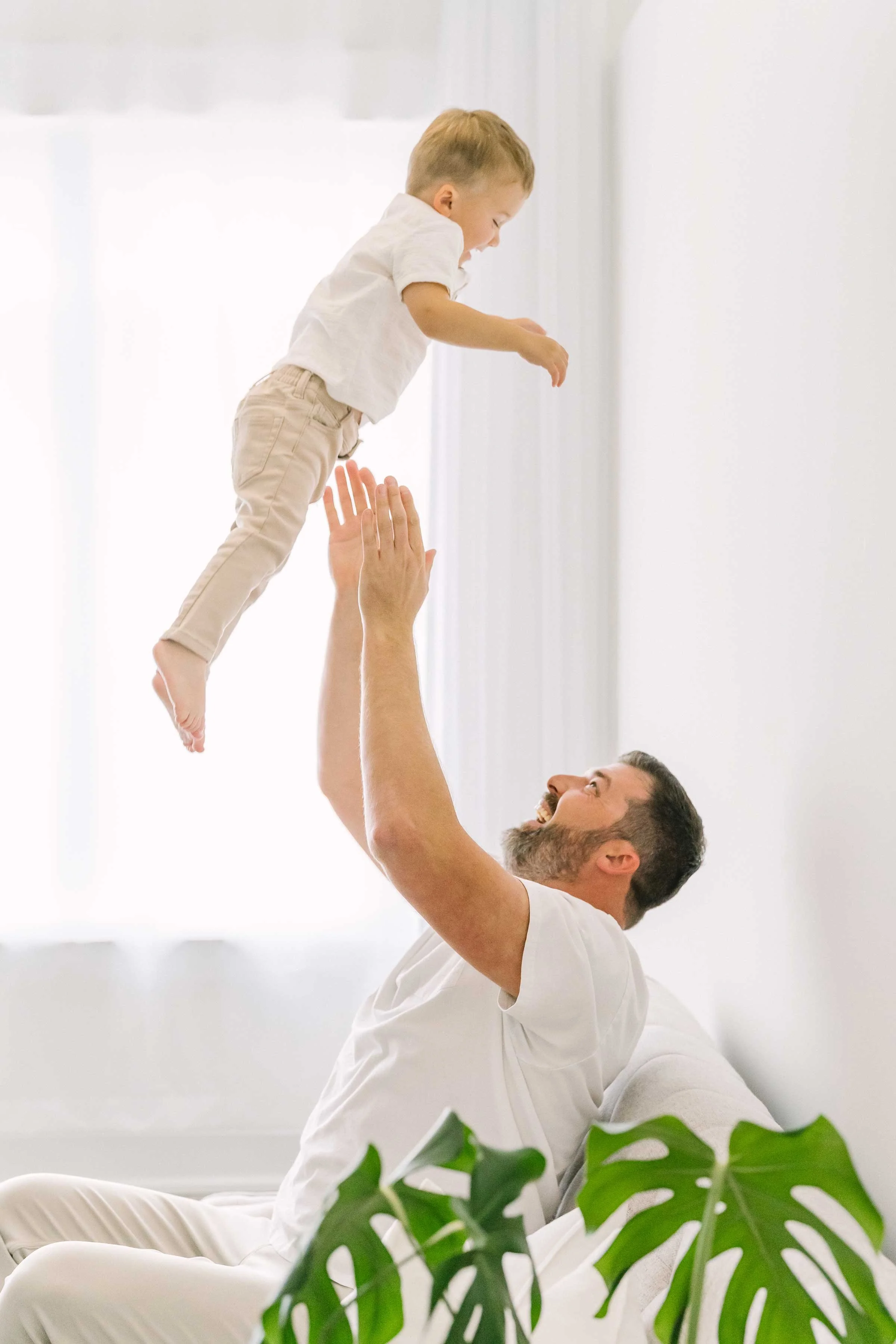 Dad tossing his laughing toddler son into the air in our Grimsby studio