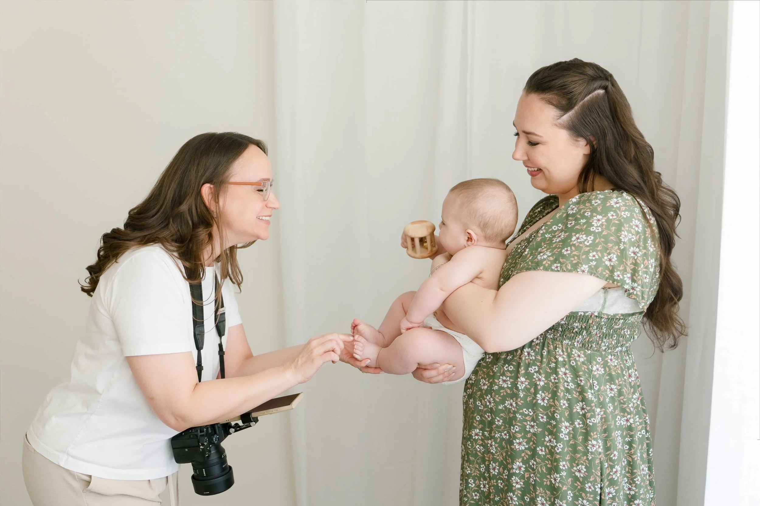 Family photographer in Hamilton showing a newborn baby to smiling mom during a family photography session