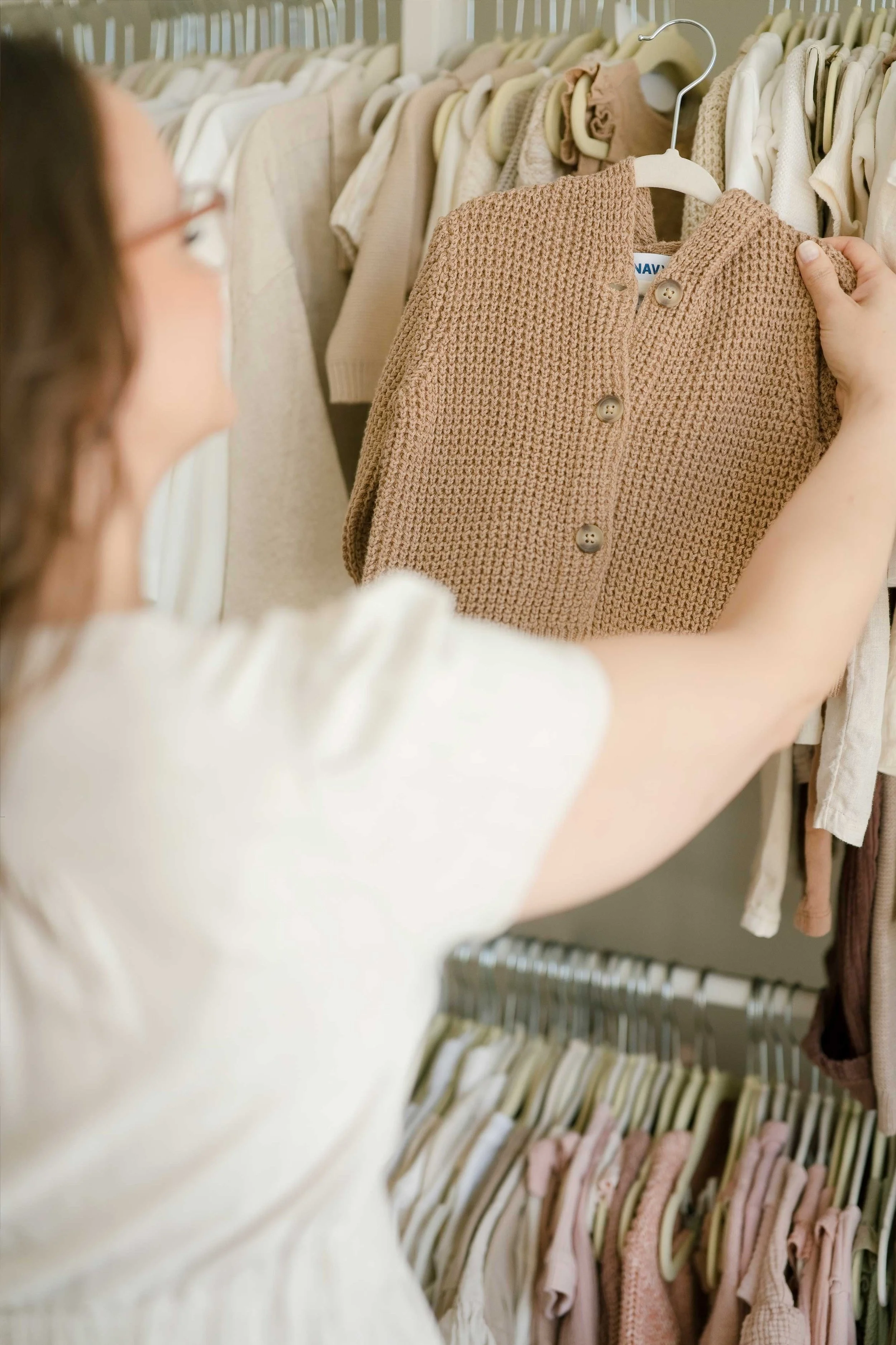 Woman browsing knit sweater on clothing rack in Grimsby photography studio