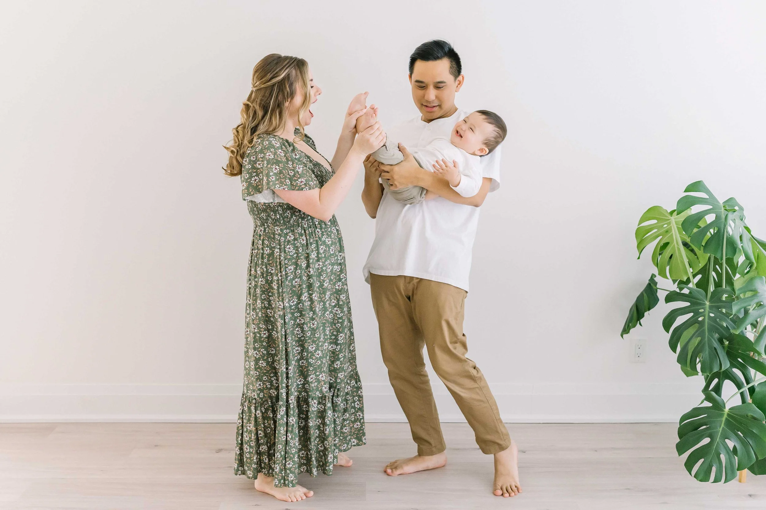 Fun family photography moment with dad swinging his baby boy in the air while everyone laughs together in the studio.