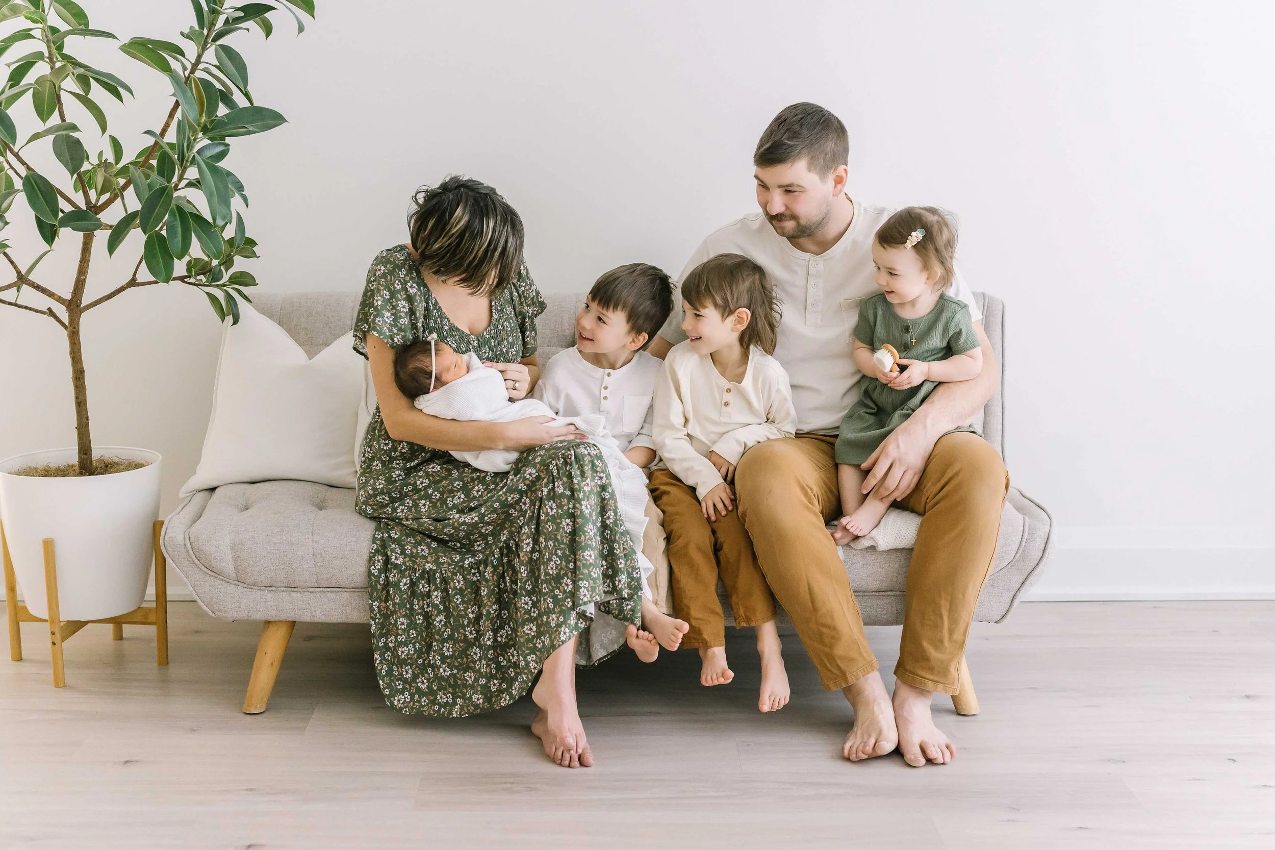 Photography in Grimsby simple newborn session setup with warm studio tones, showing the whole family while mom holds the newborn.