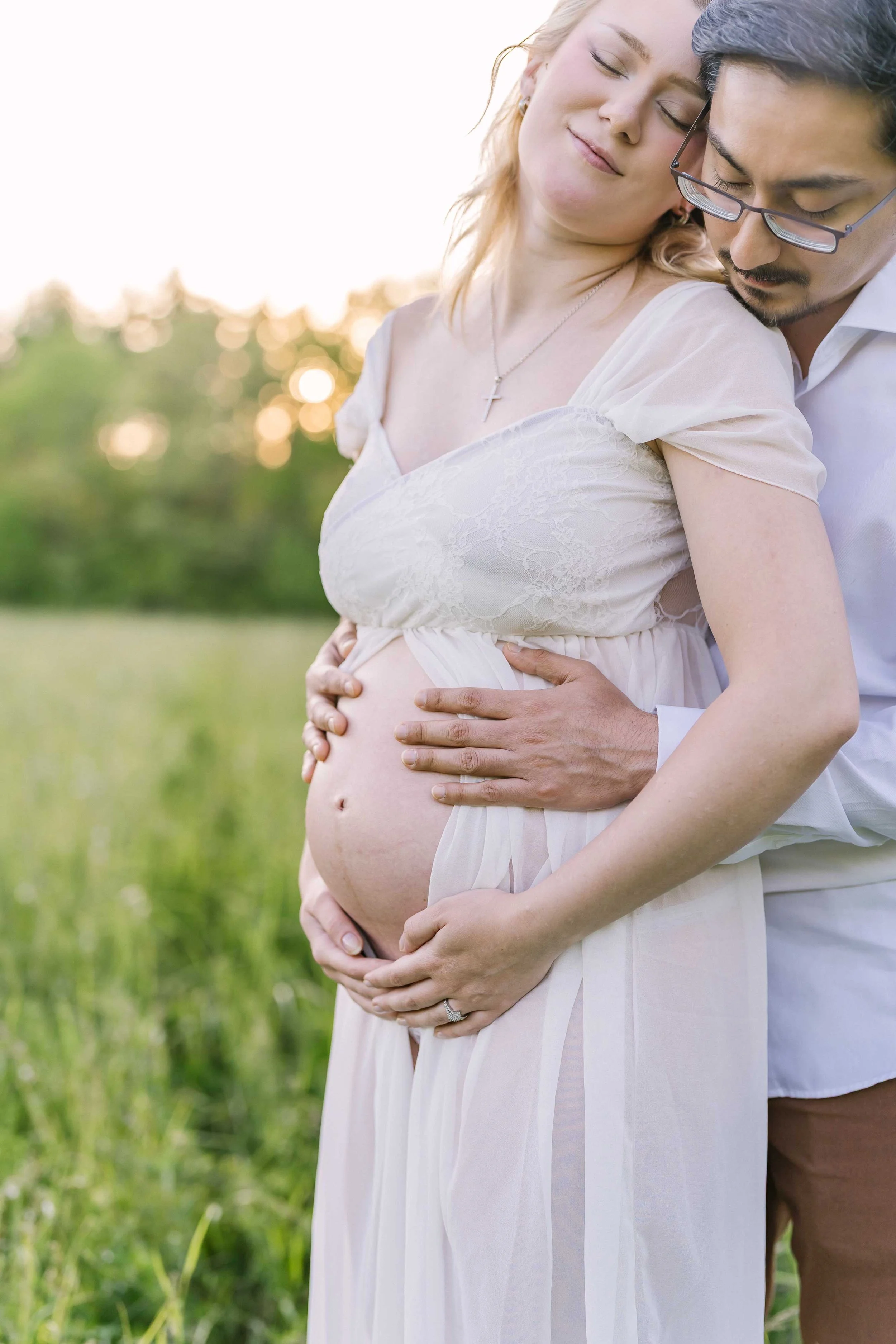 Expectant couple relaxing together in tall grass during a Grimsby maternity session