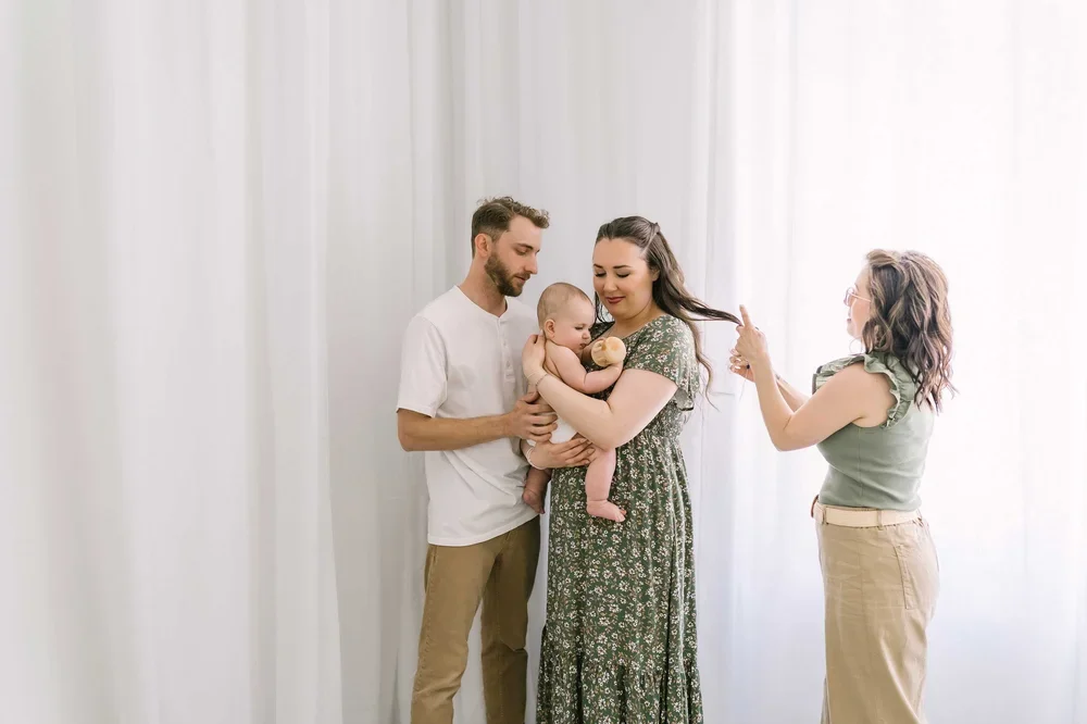 Karen Byker, newborn photographer in Niagara, adjusting hair for a couple