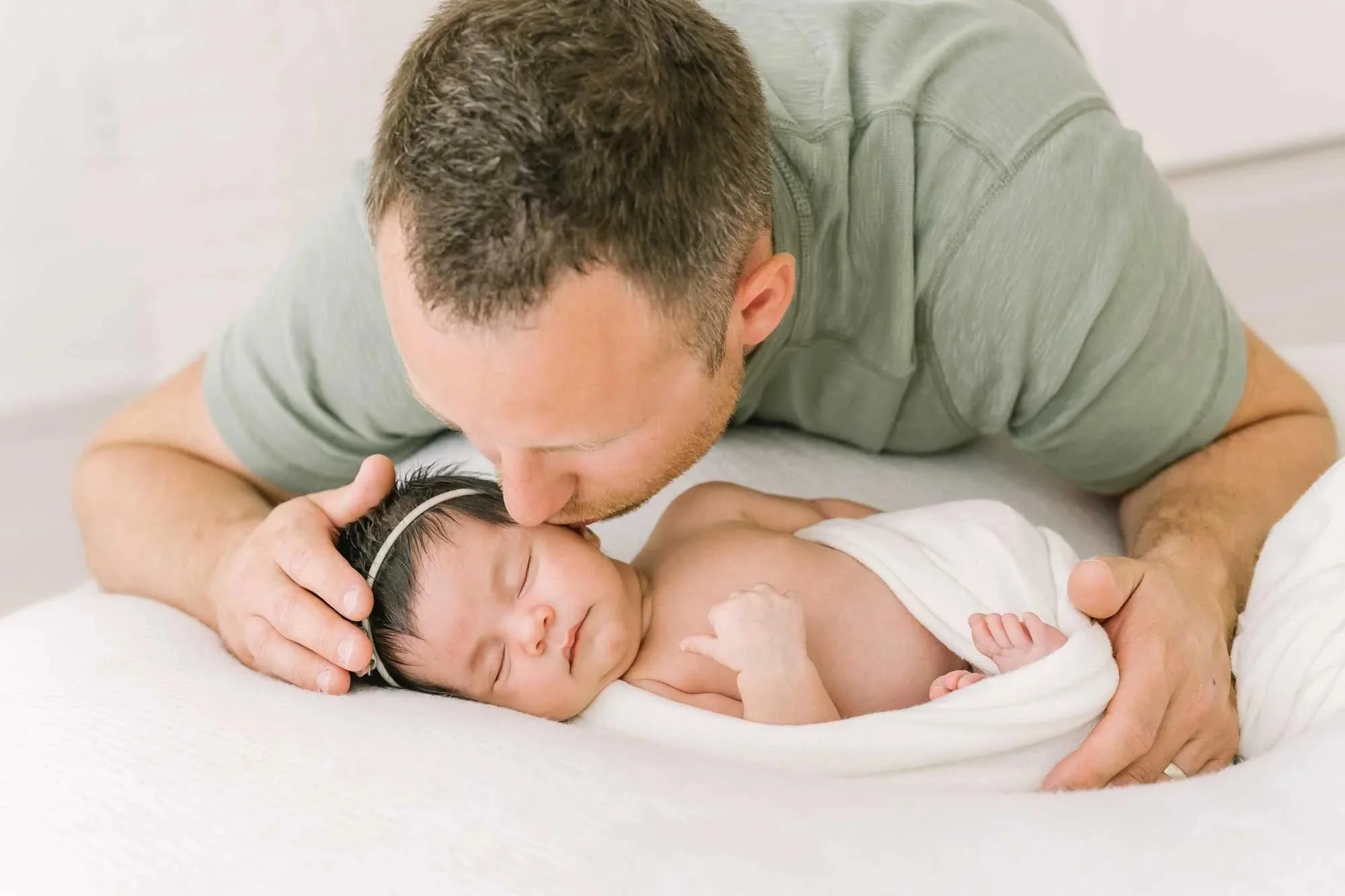 Close up of dad kissing newborn baby at newborn photography studio in Hamilton ontario​