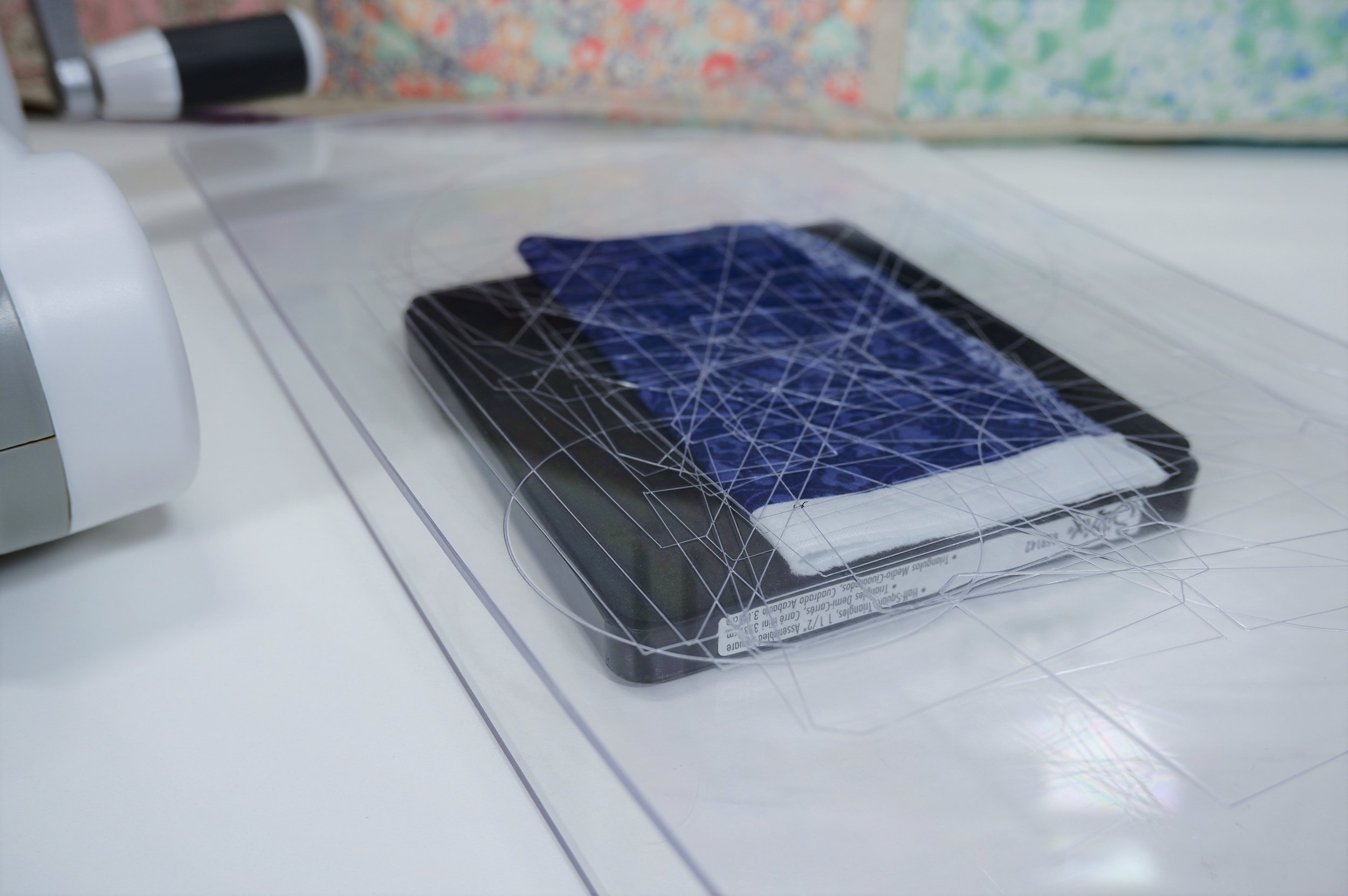 Finally, lets make our last Sizzix sandwich. Place your cutting pad down first. Next stack your Half-Square Triangles, 1 1/2" Assembled Square - die on top - foam side up. Place 2 layers of print fabric on top of that - making sure to cover up all of the die cut lines. Then place your second cutting pad on top of the fabric.