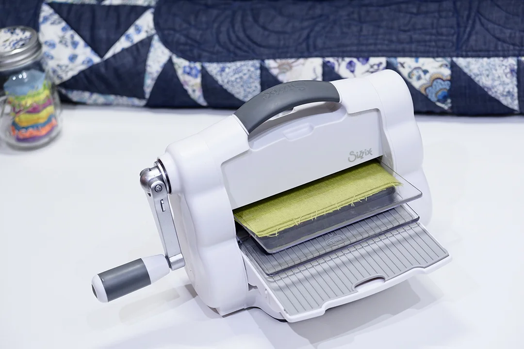 The first step will be to cut out your pieces. To make your Sizzix sandwich - start with your cutting pad and place your die on top, foam side up and slightly askew. Then stack on 6 layers of linen over the cactus and 2 pink fabric scraps over the flower cutout. Place the 2nd cutting pad on top and your Sizzix sandwich is complete. Now feed the sandwich through the machine and you’ve got all your pieces set to assemble.