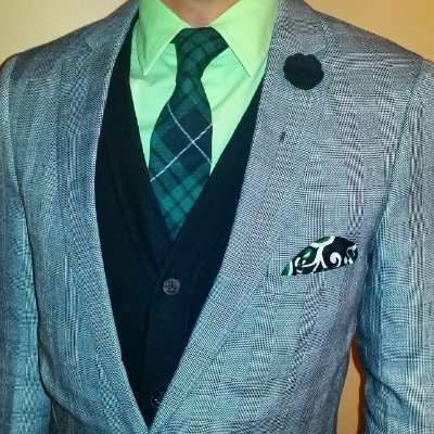 A mint shirt and subtly plaid grey blazer complement the tie and lapel pin in the green version of the Hamilton Box.
