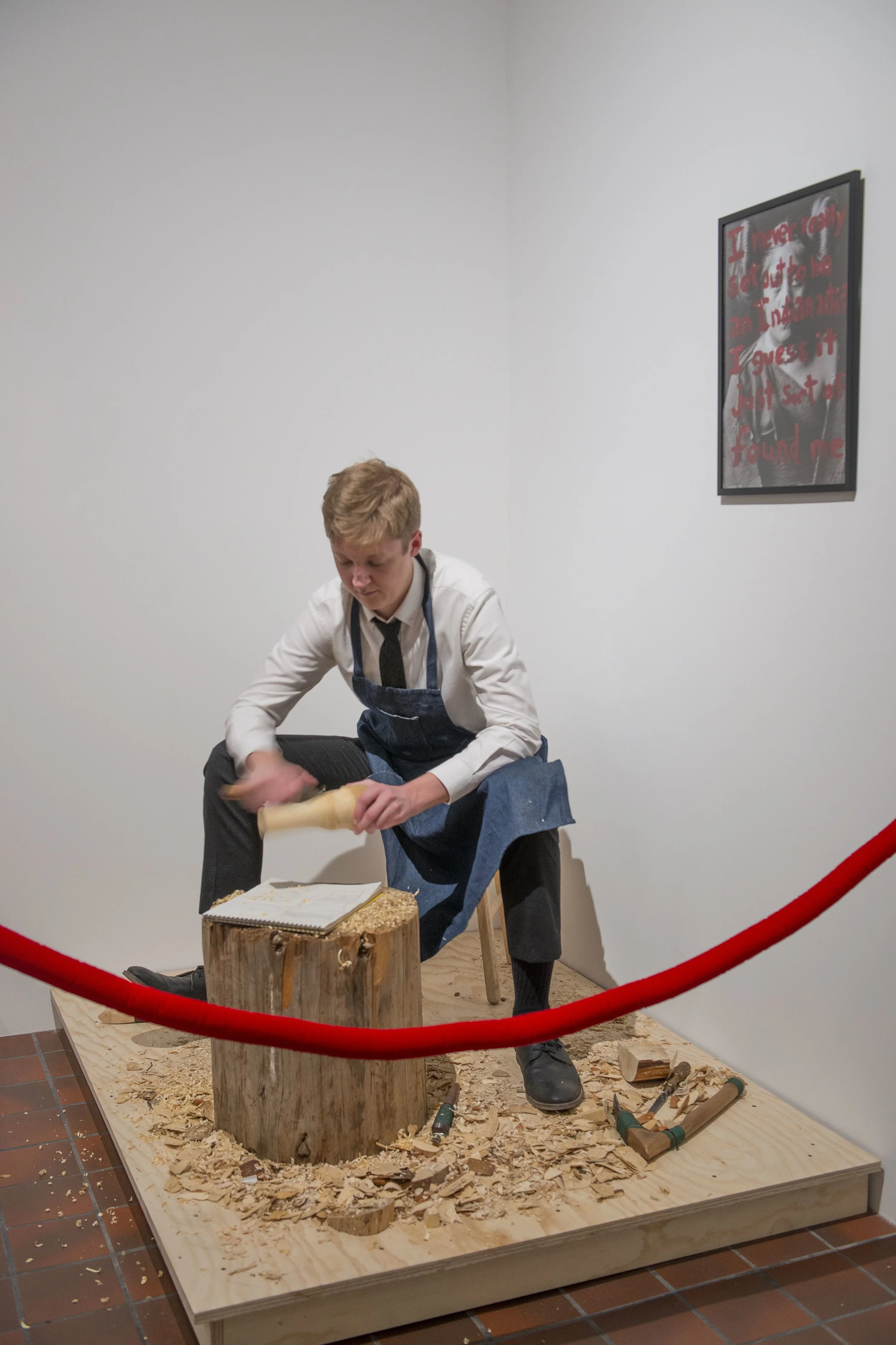 White Carver, velvet rope, wood stump, wooden platform, white male performer, 2012-present.