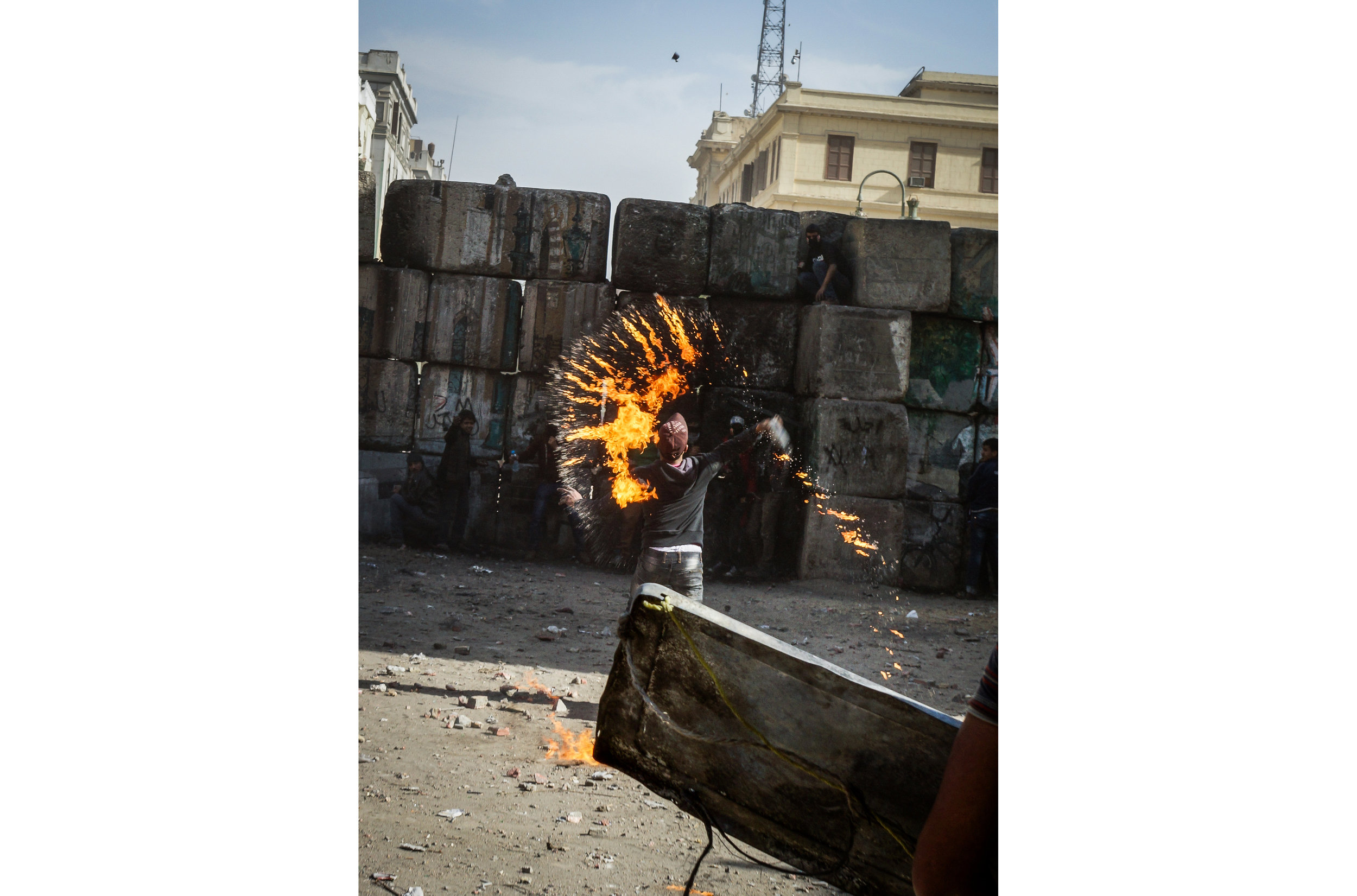 A protester throws a broken Molotov cocktail over a block wall at police guarding the Interior Ministry. 