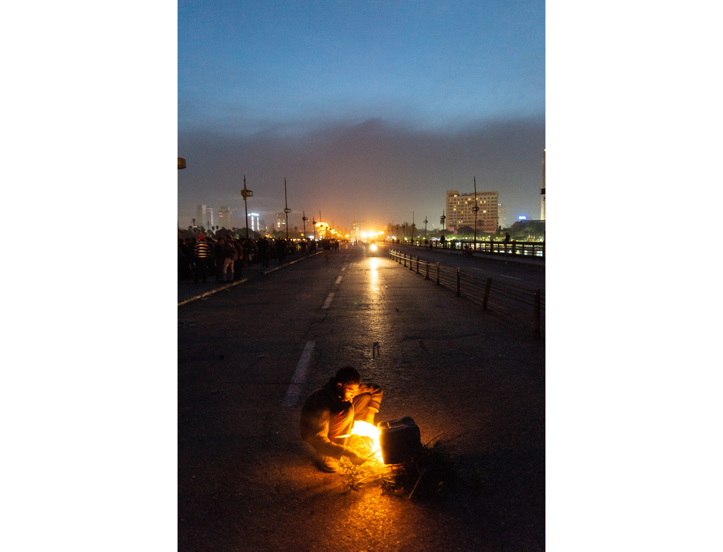 A boy stokes a fire in the eastbound lanes of the Qasr Al Nil Bridge. March 7, 2013  