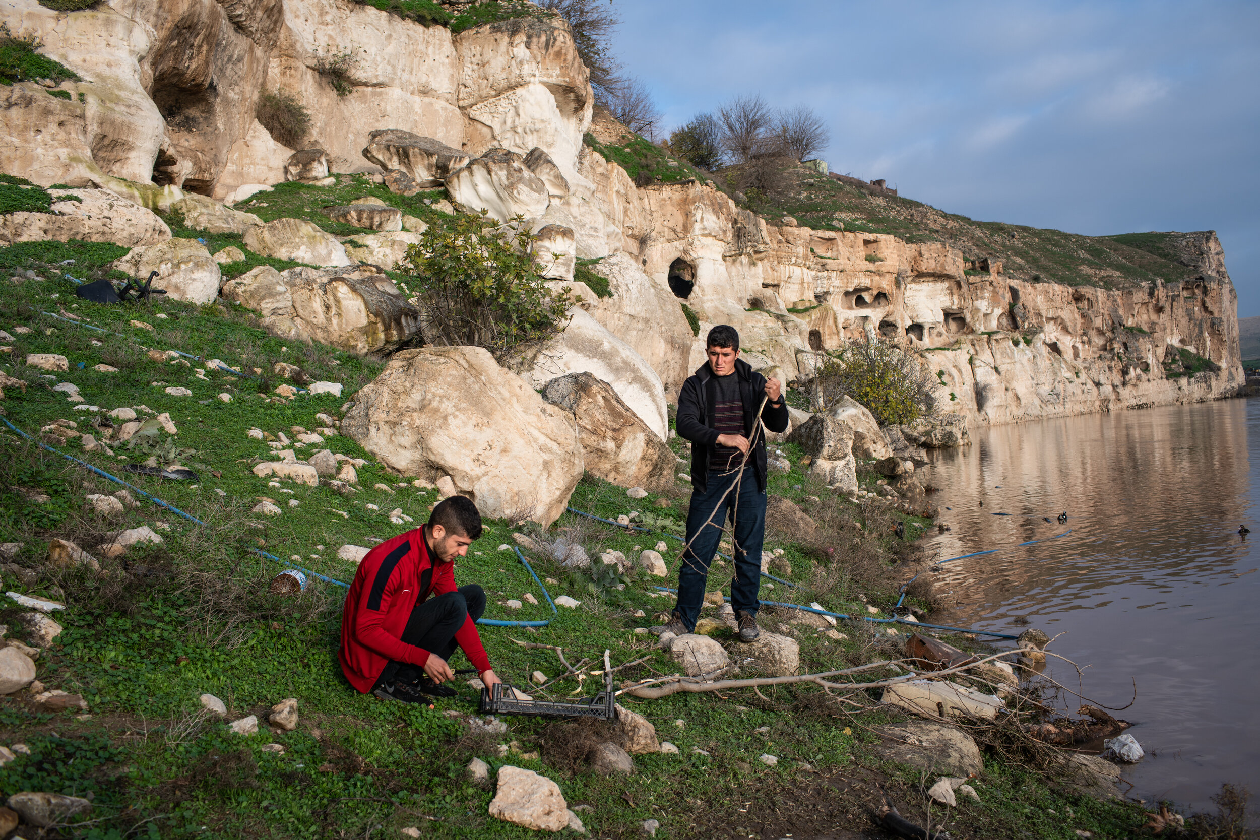Young men prepare a fire beneath ancient caves on the northern bank of the Tigris River