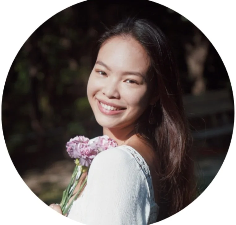 Smiling person holding pink flowers outdoors