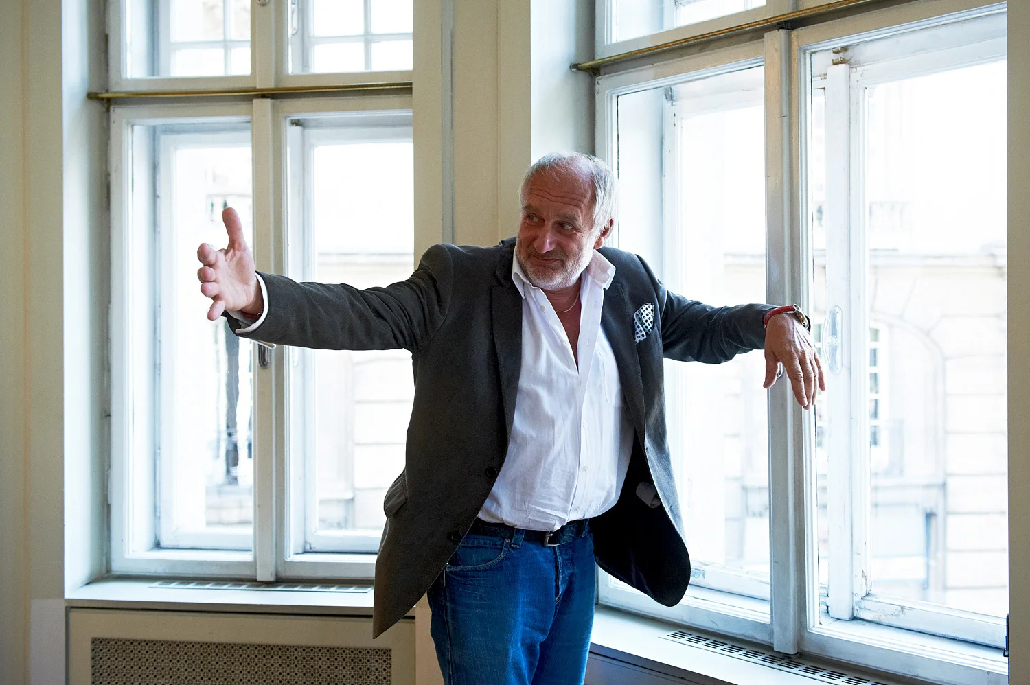 Mann lehnt an Fenster und macht eine große Geste mit seiner rechten Hand .