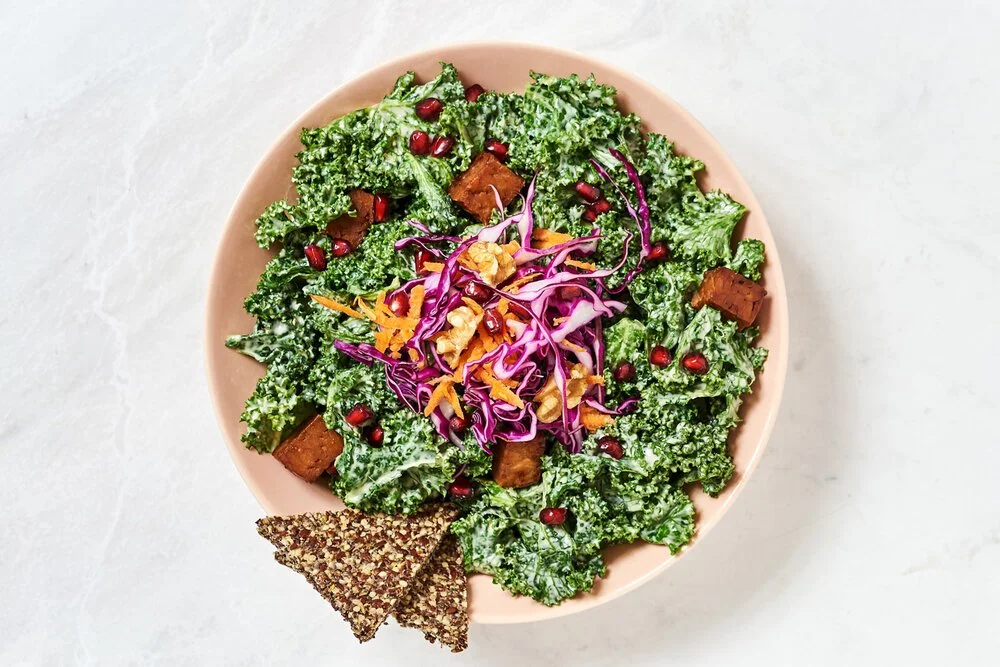 Food Aufnahme einer Schüssel mit Kale Salad und Kracker auf weißer Marmorplatte