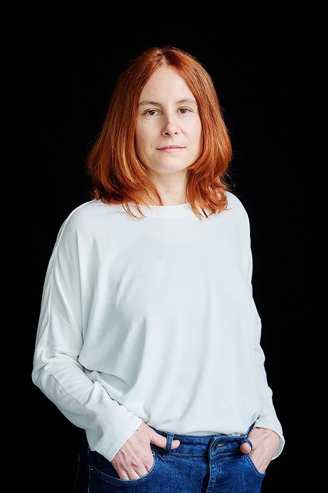 Foto einer Frau in weißem oversize Shirt und roten Haaren vor schwarzem Hintergrund