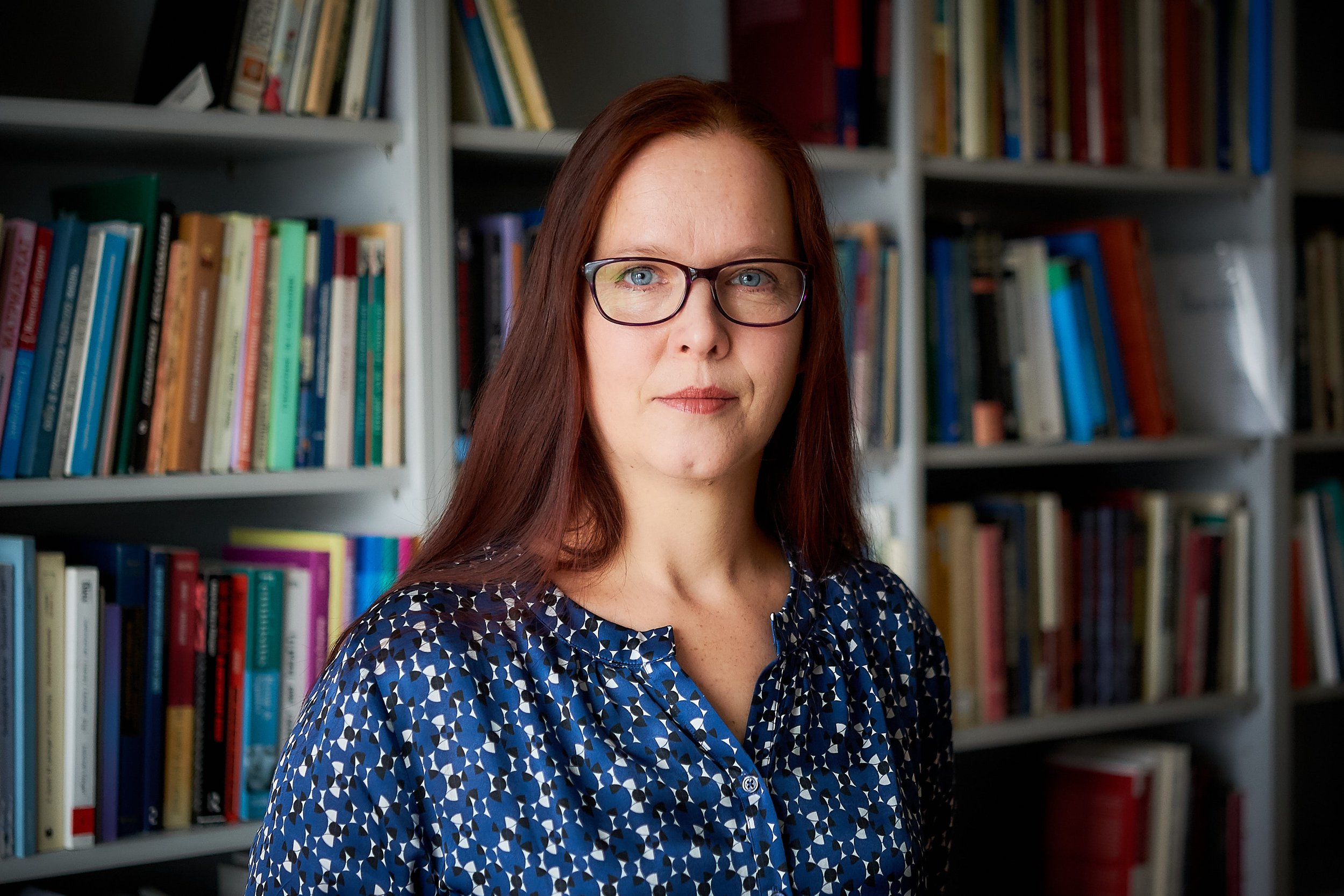 Frau mit Brille vor Bücherregal