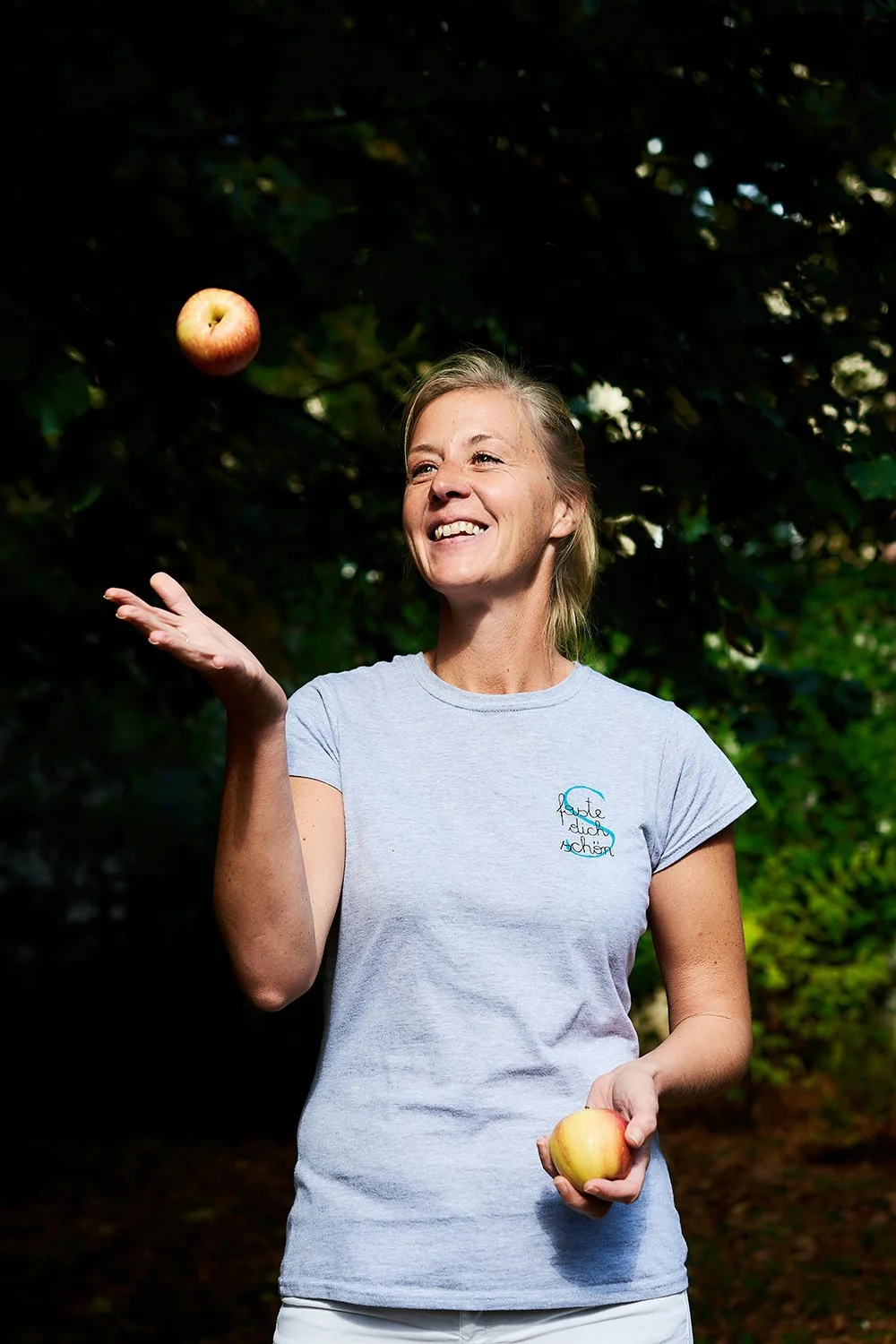 Frau wirft Apfel, lächelt und sieht dabei auf Apfel