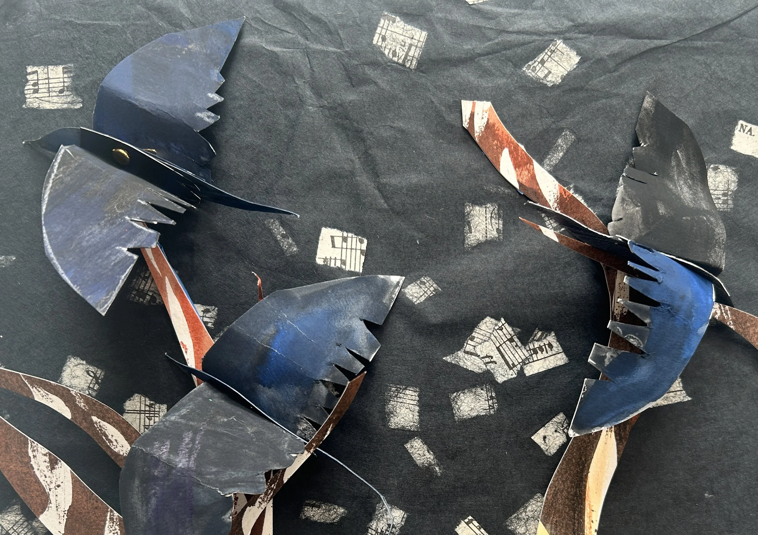 
Building the crows — layered cut paper, brass brads, and thread allow each wing and body segment to move independently. I use Sakura Poster Color on the birds and trees--- handmade paper for the backgrounds. 