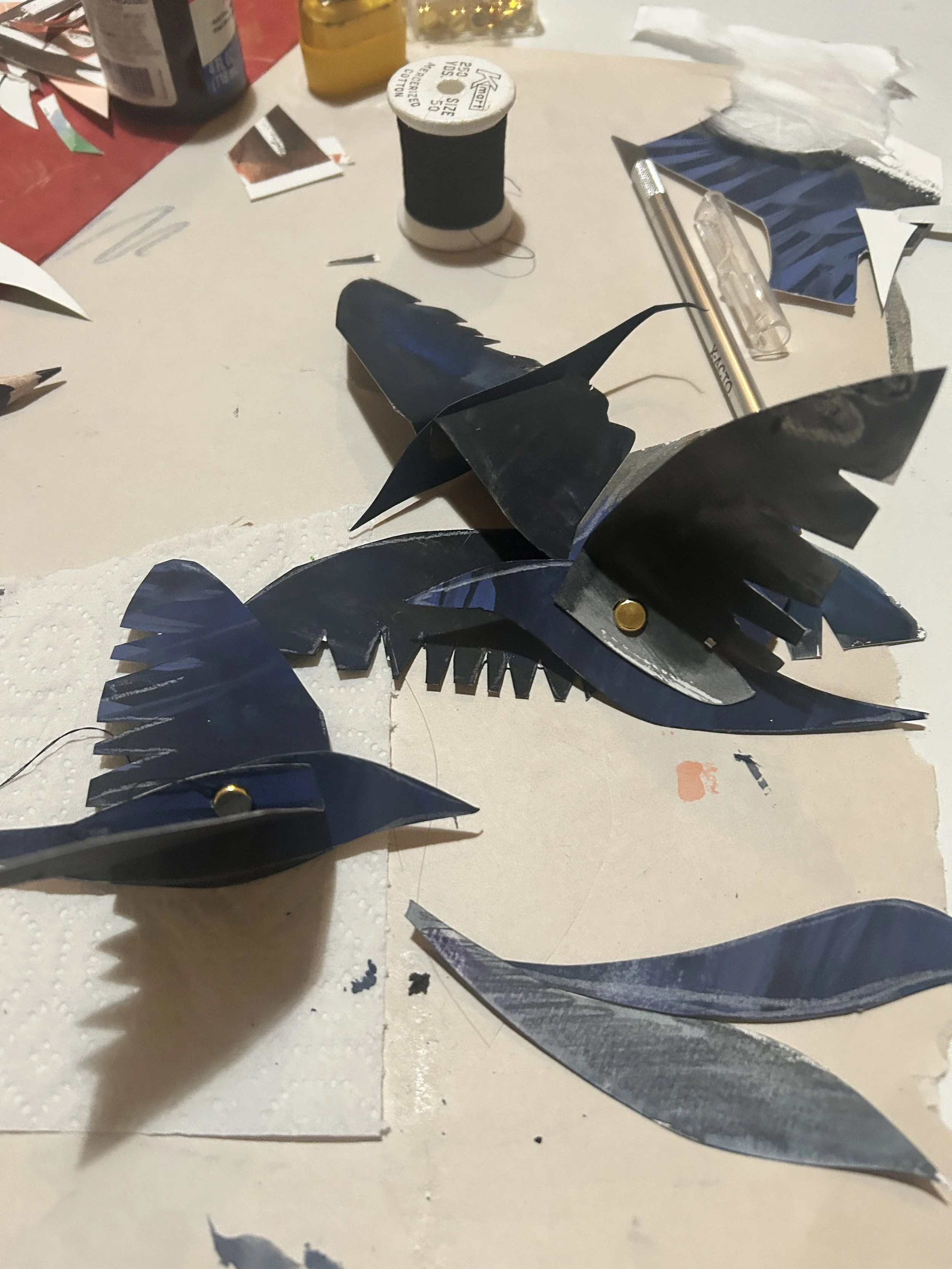 The crow flock — articulated cut paper puppets with painted and stamped backgrounds, ready for the set.
