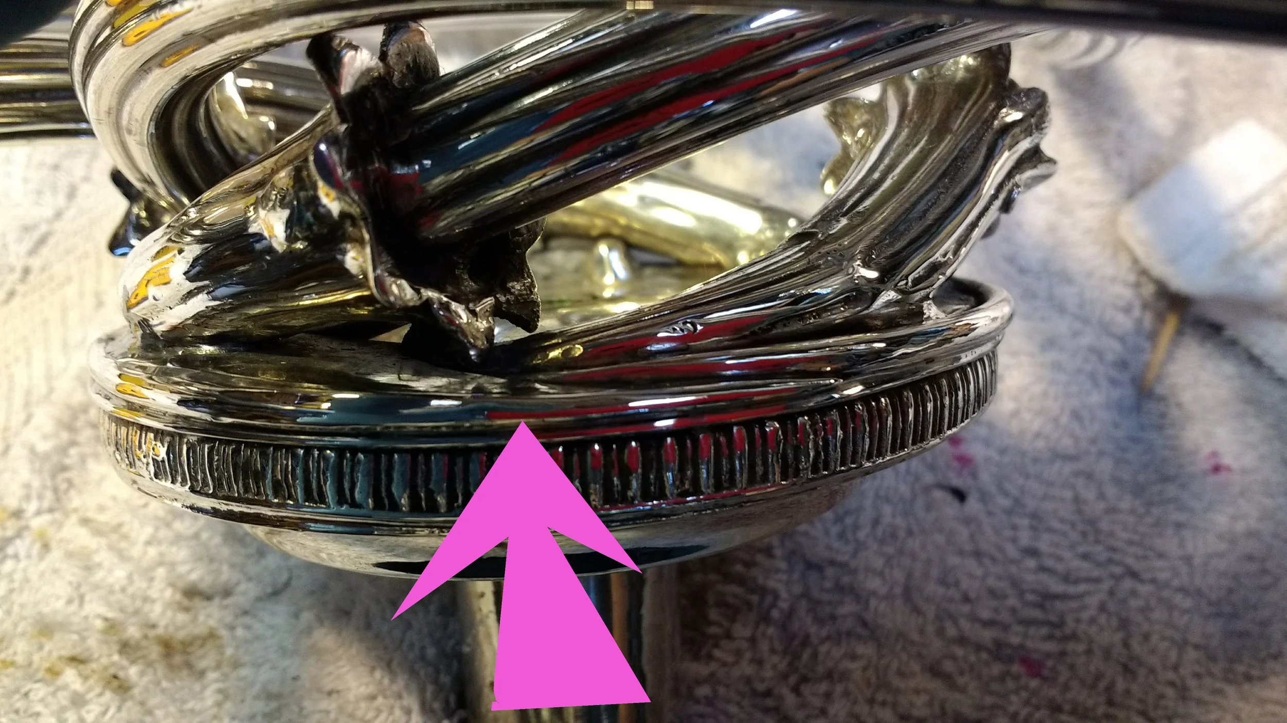 The arrow points to the tappered sterling wire concealing and reinforcing the repair.