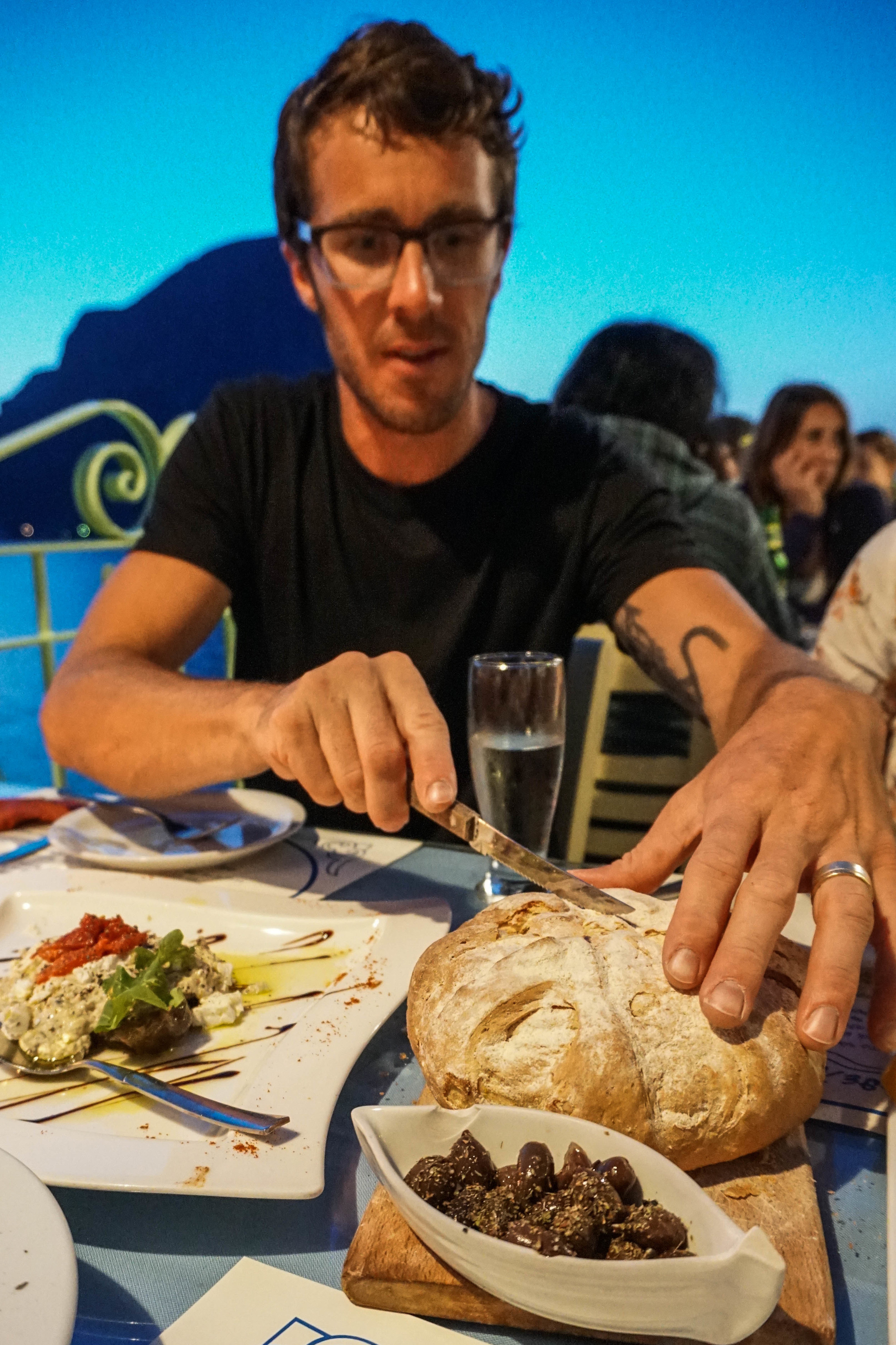Michael cutting into fresh baked bread at the Aegean