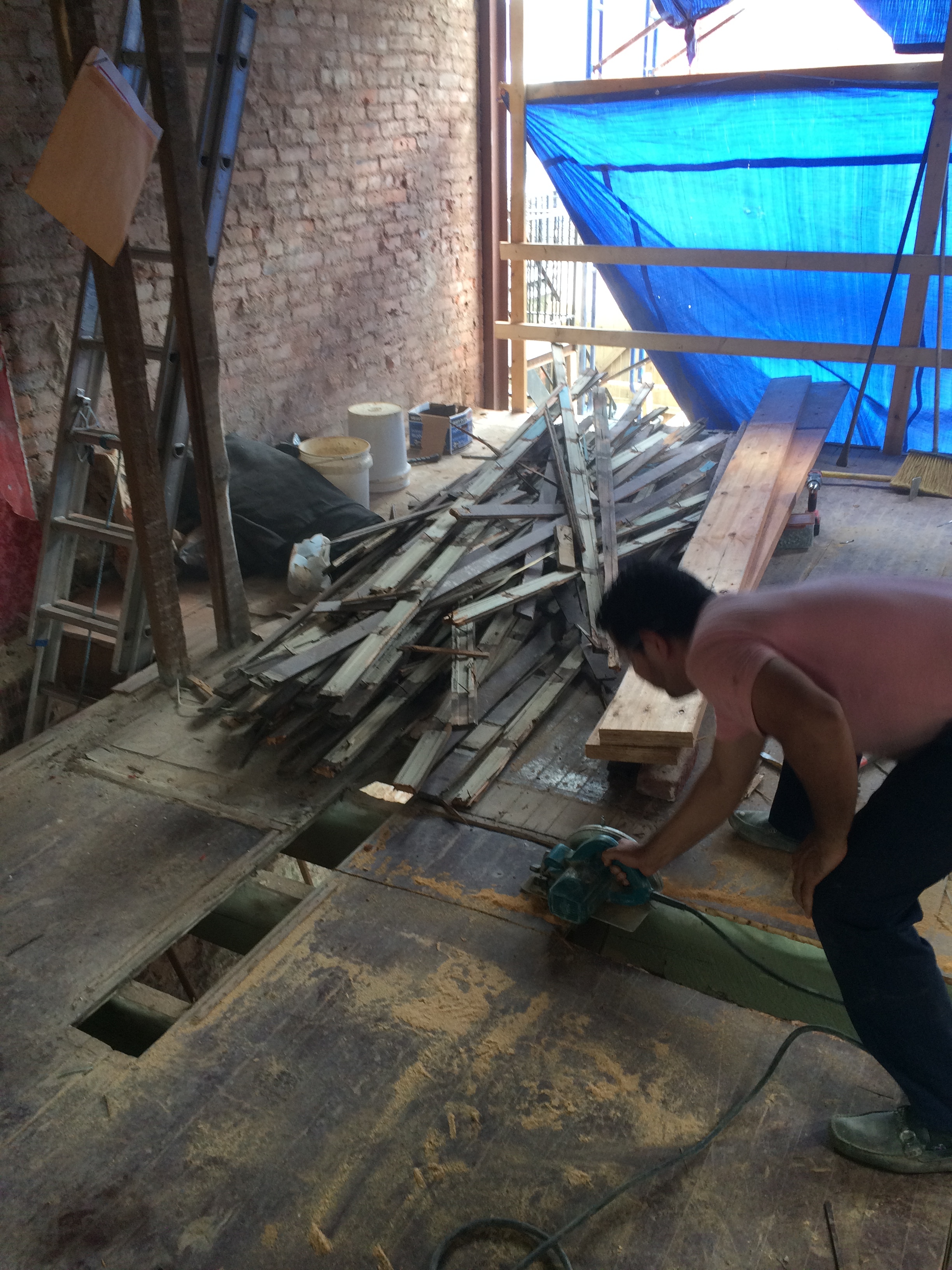 Removing a section of the old subfloor to create a space for installing the new beam in the floor framing