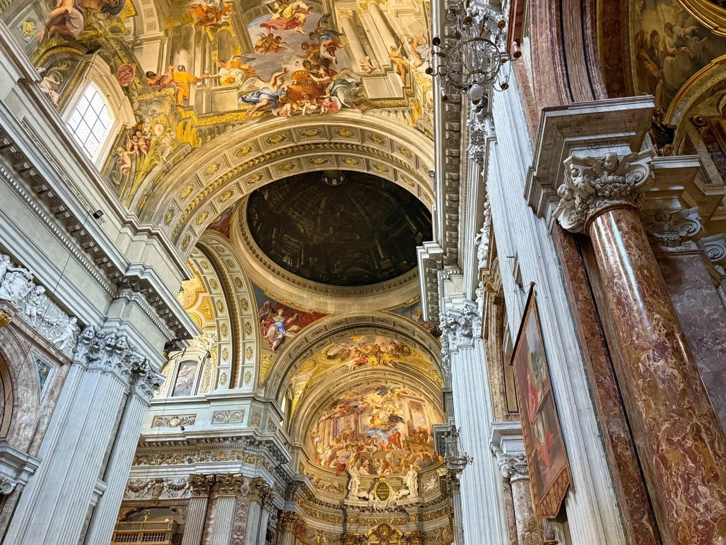The kind of ceiling that makes you stop mid-conversation and just look up.

Rome does this to you. You walk into a church &mdash; no queue, no ticket, no plan &mdash; and suddenly you are standing beneath centuries of gold, marble, and painted drama.