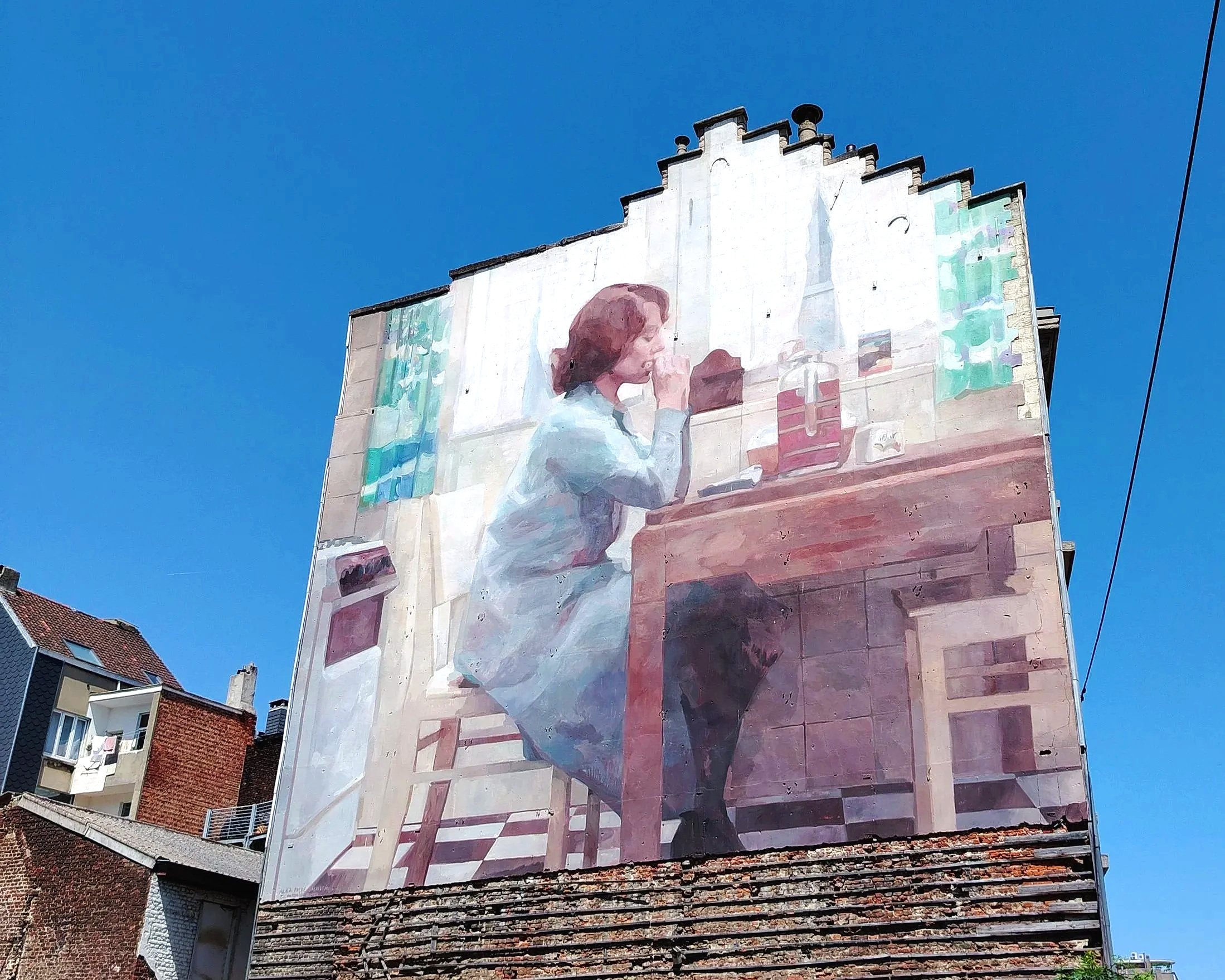 Grote muur met een muurschildering van een vrouw die piano speelt, onder een heldere blauwe hemel en omringd door gebouwen.