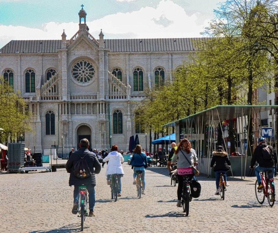 Groep Nederlandse toeristen fietst op de Vismarkt naar de Sint-Katelijne kerk in Brussel met gids. Sommigen hebben een e-bike gehuurd.
