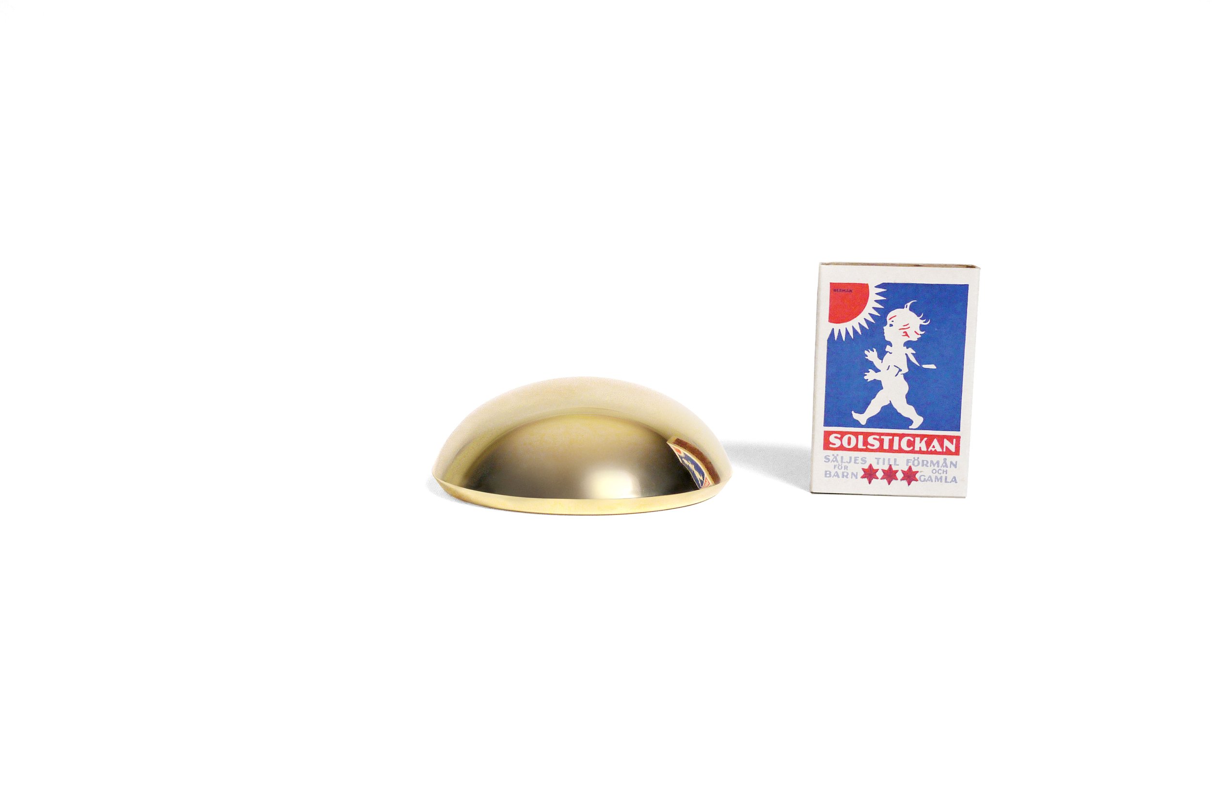 Round paperweight side-by-side with matchbox for scale, on white background