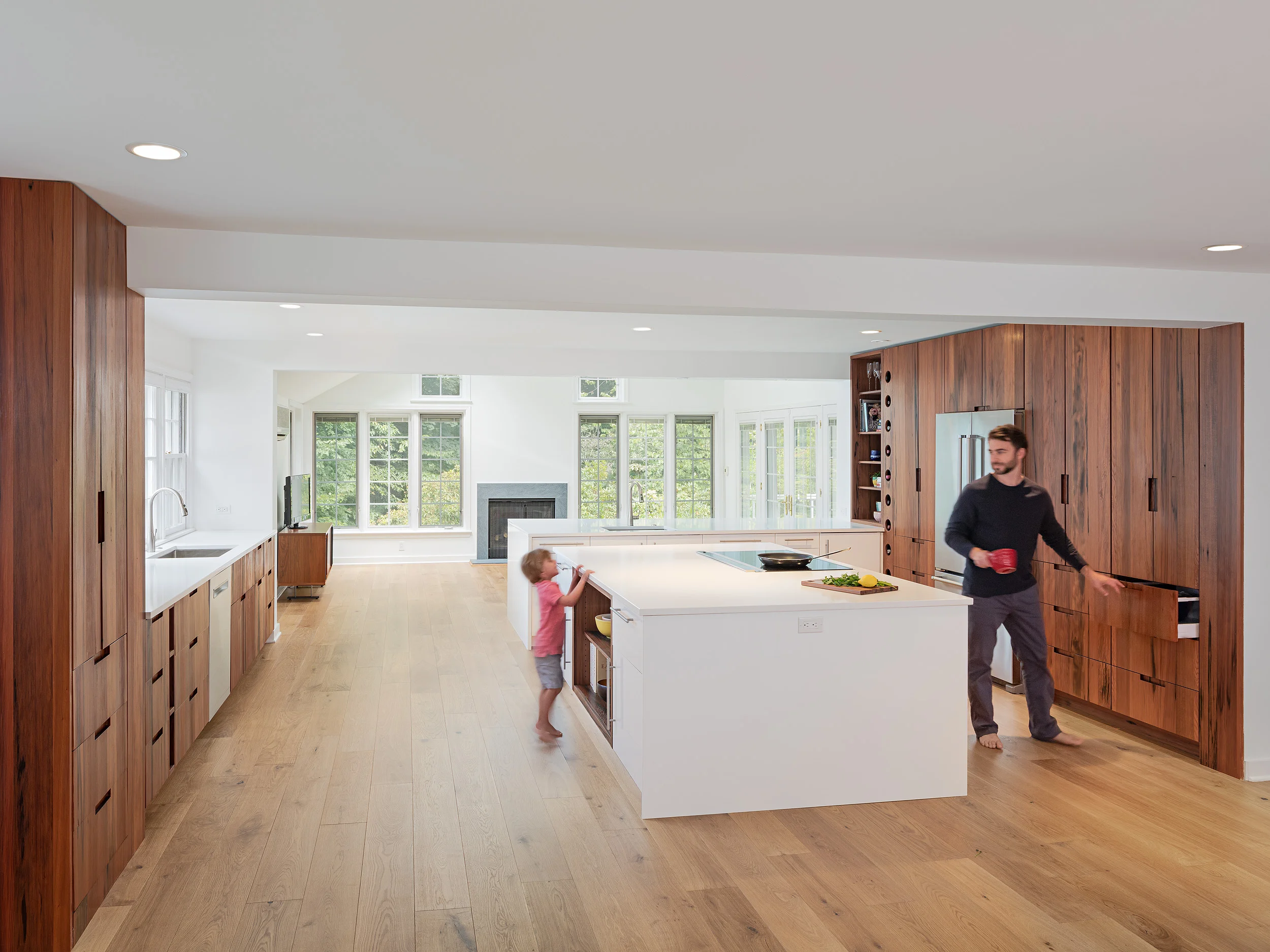  Adding in a large white island with an integrated bookcase alongside the peninsula with bar seating and additional cabinet storage created a dramatic simplicity that met the family’s needs as well as their aesthetic. 