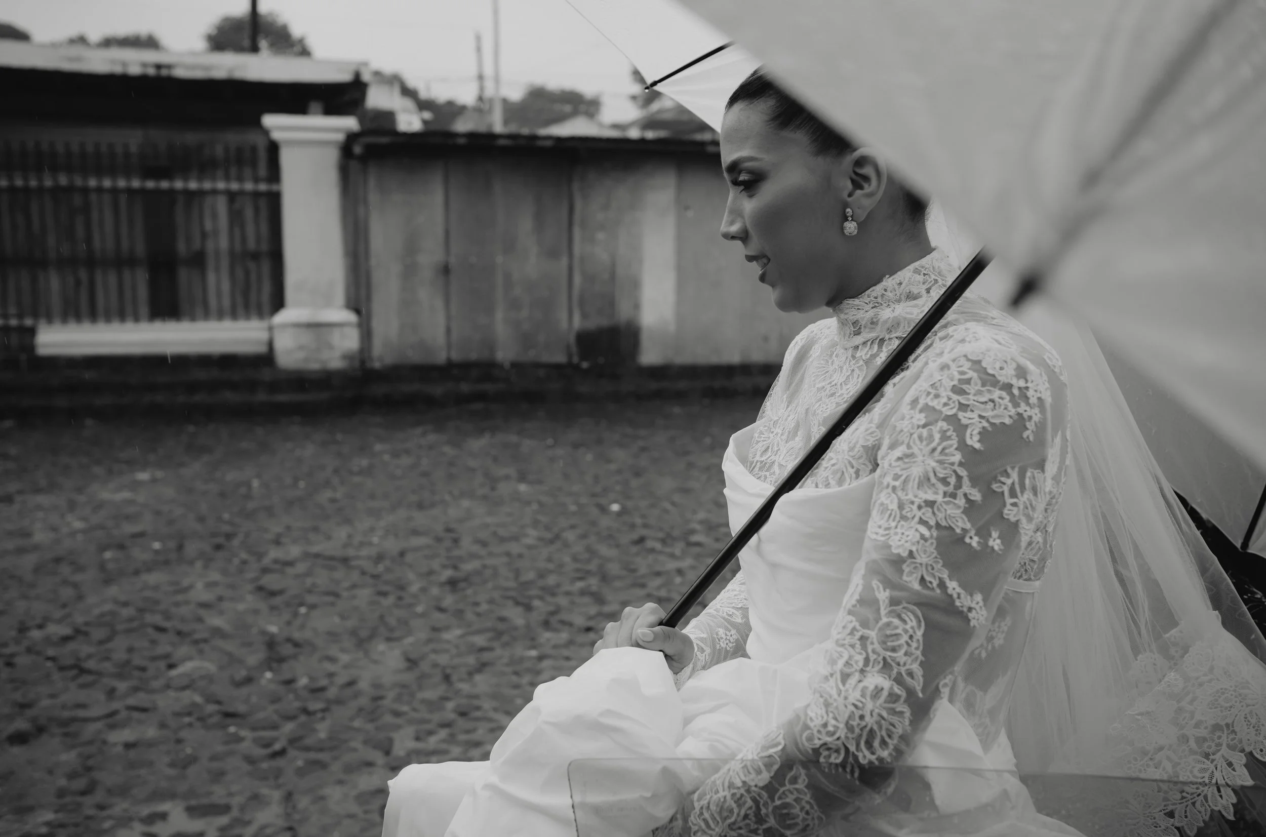Bride smiling beneath an umbrella during a rainy season destination wedding in Antigua Guatemala.