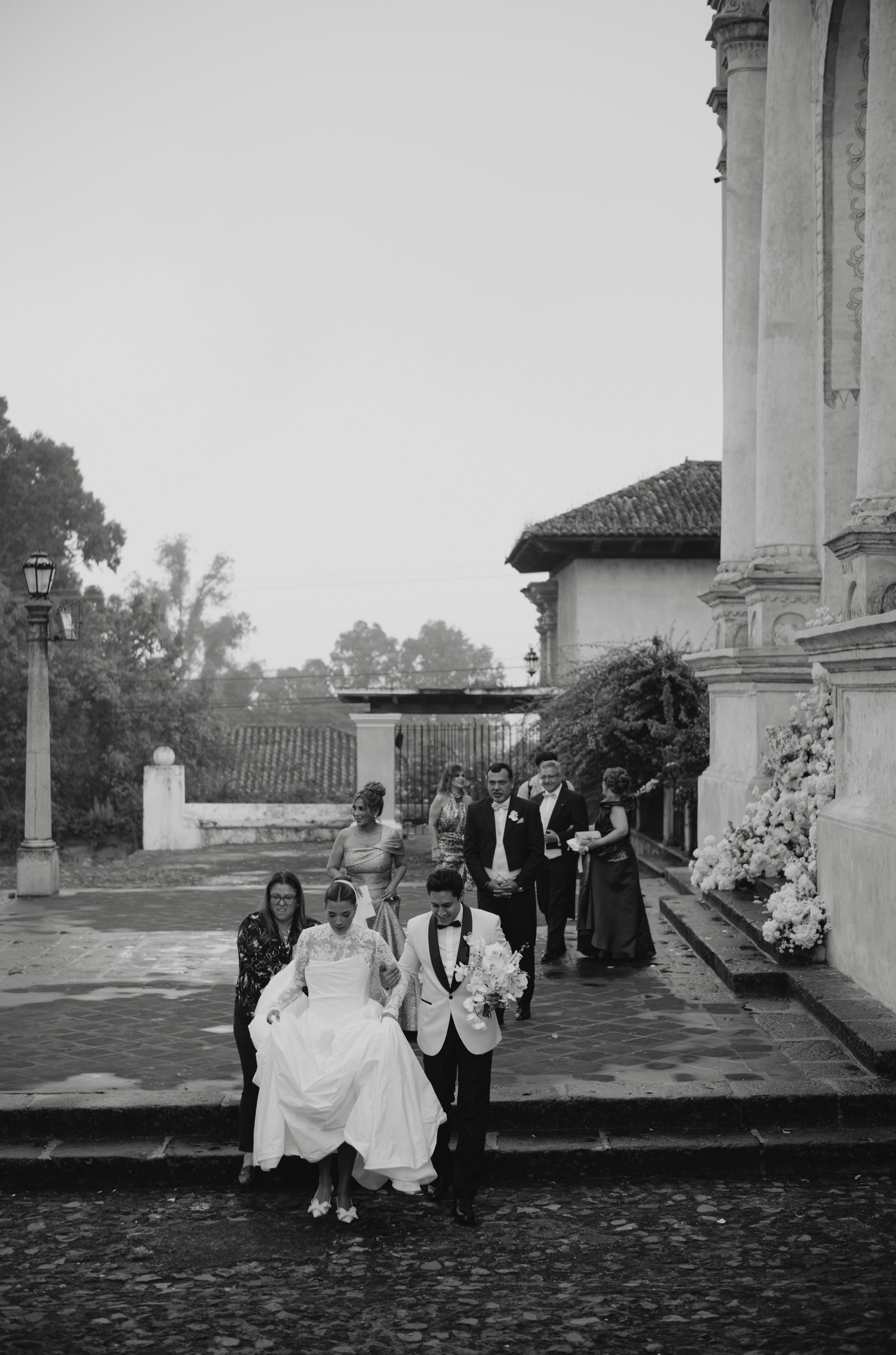 Wedding guests arriving with umbrellas during a rainy season destination wedding ceremony in Antigua Guatemala.