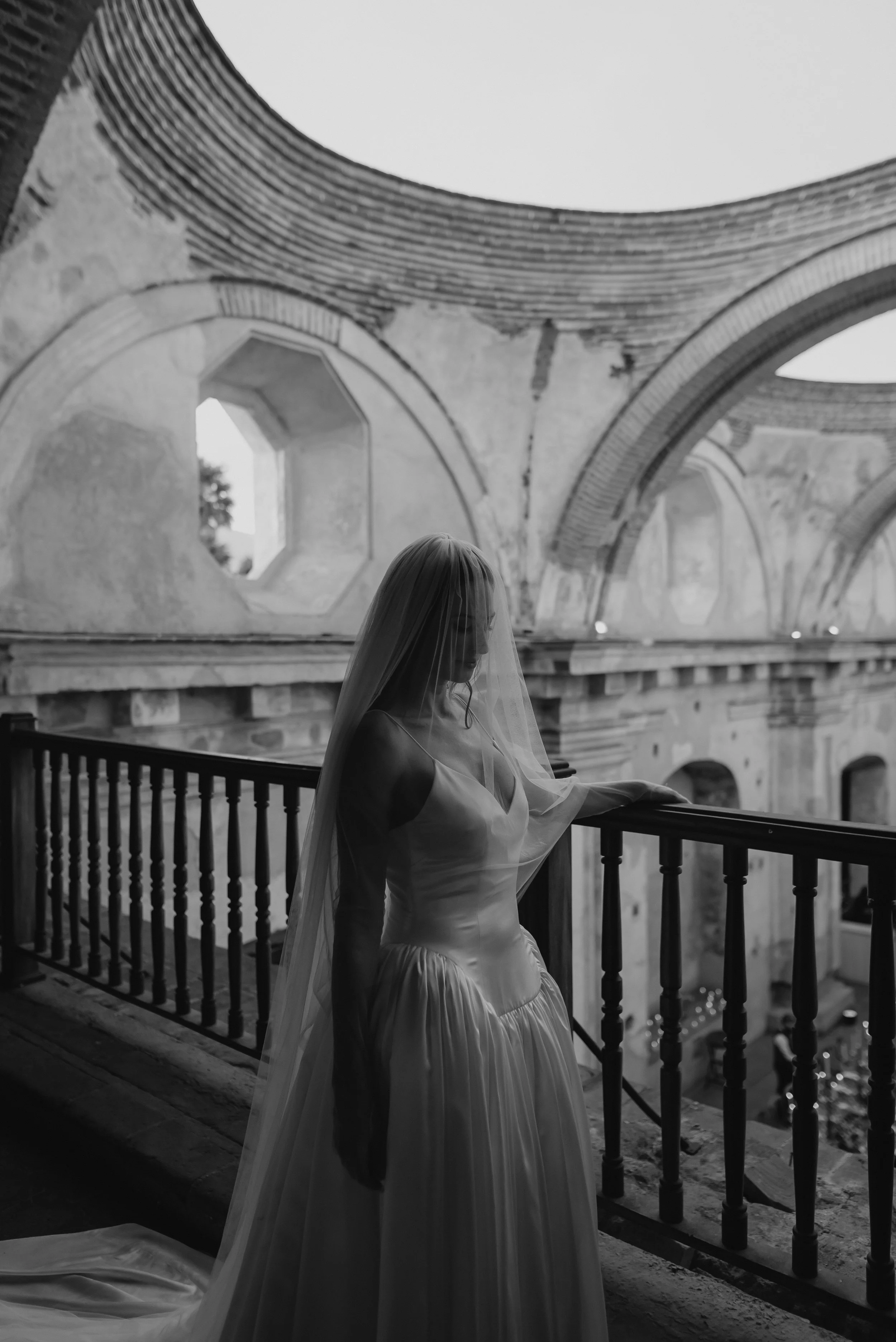 Black and white bridal portrait beneath the open-air arches of Santa Clara Ruins in Antigua Guatemala.