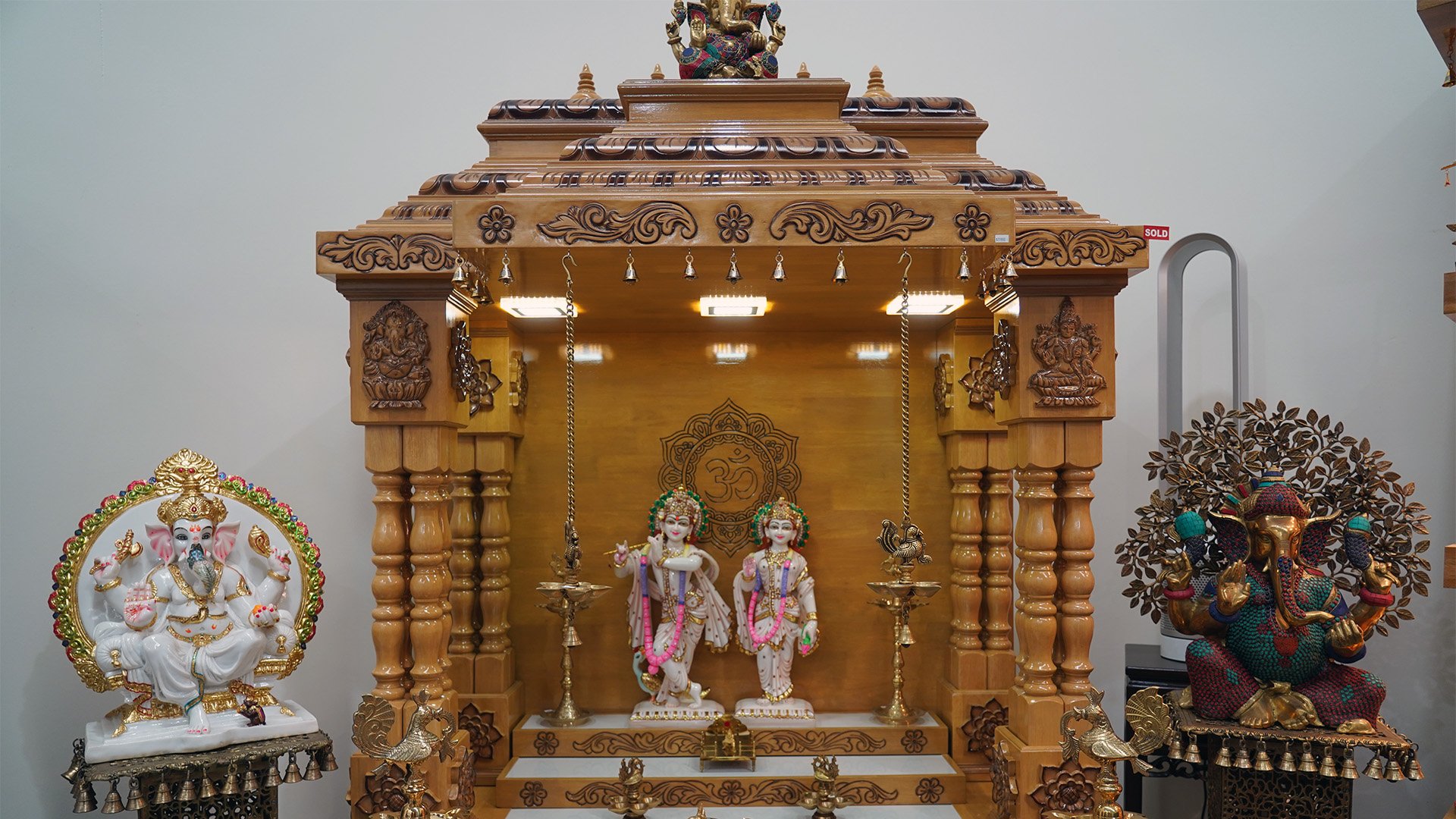 Large handcrafted wooden mandir featuring detailed carvings, pillars, and LED lighting, designed as a traditional Hindu home temple for daily prayer and worship.