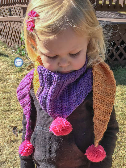 My "mod scarf" patterns are some of my favorites, so I decided to make a mini version for my daughter! This simple and modern scarf is adorned with pom poms and is perfect for children. Keep reading for the free crochet pattern.