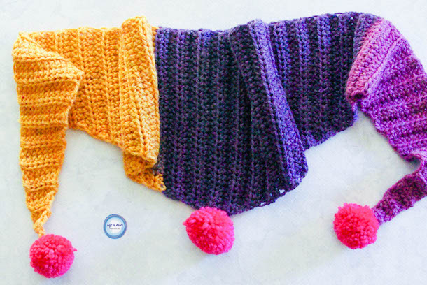 My "mod scarf" patterns are some of my favorites, so I decided to make a mini version for my daughter! This simple and modern scarf is adorned with pom poms and is perfect for children. Keep reading for the free crochet pattern.
