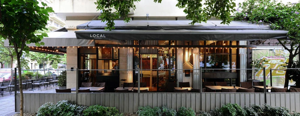 Local Espresso Bar on P.P. Germanou street, featuring its café on the left and a deli/snack restaurant on the right