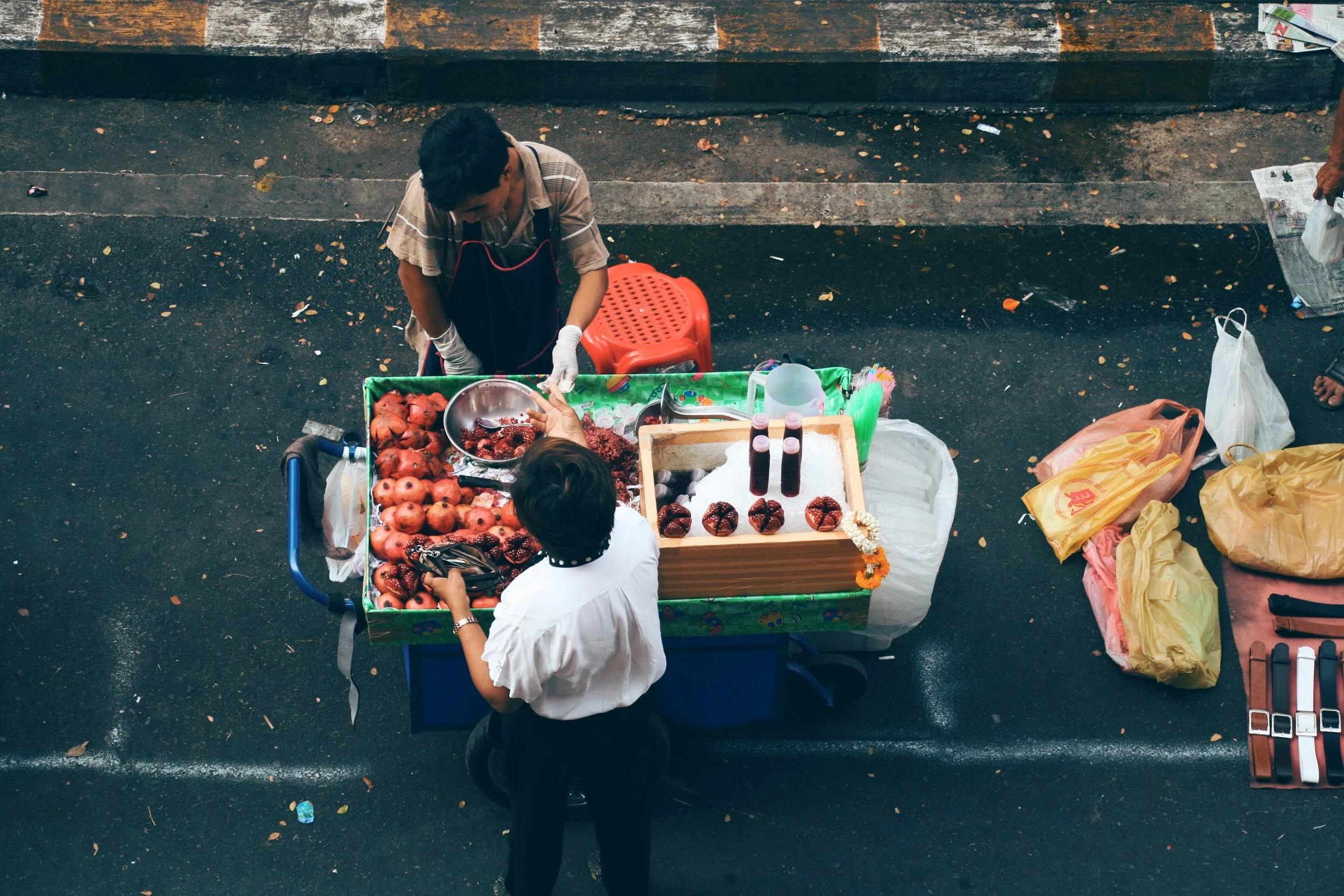 Fresh fruit vendor selling whole pomegranates or juice in a bottle