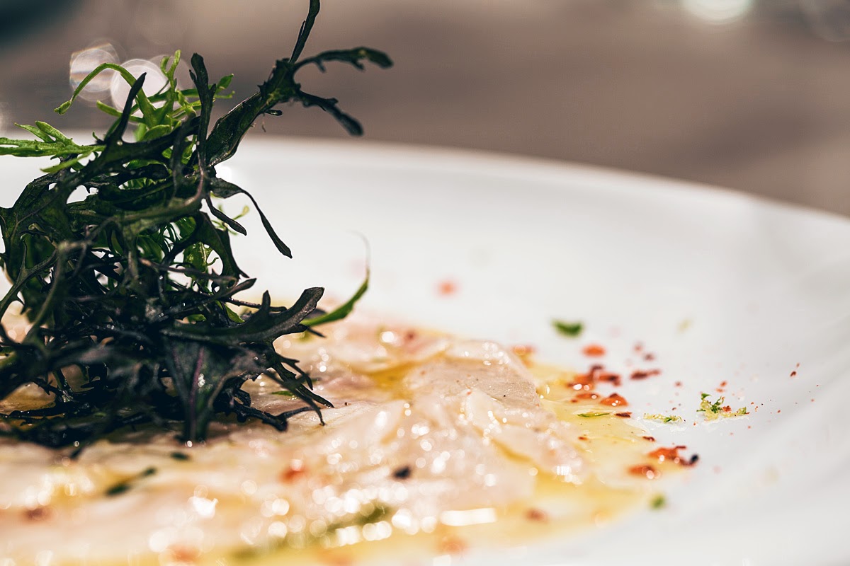 Seabass carpaccio sprinkled with citrus zest, chilli drops and a dash of wild rocket