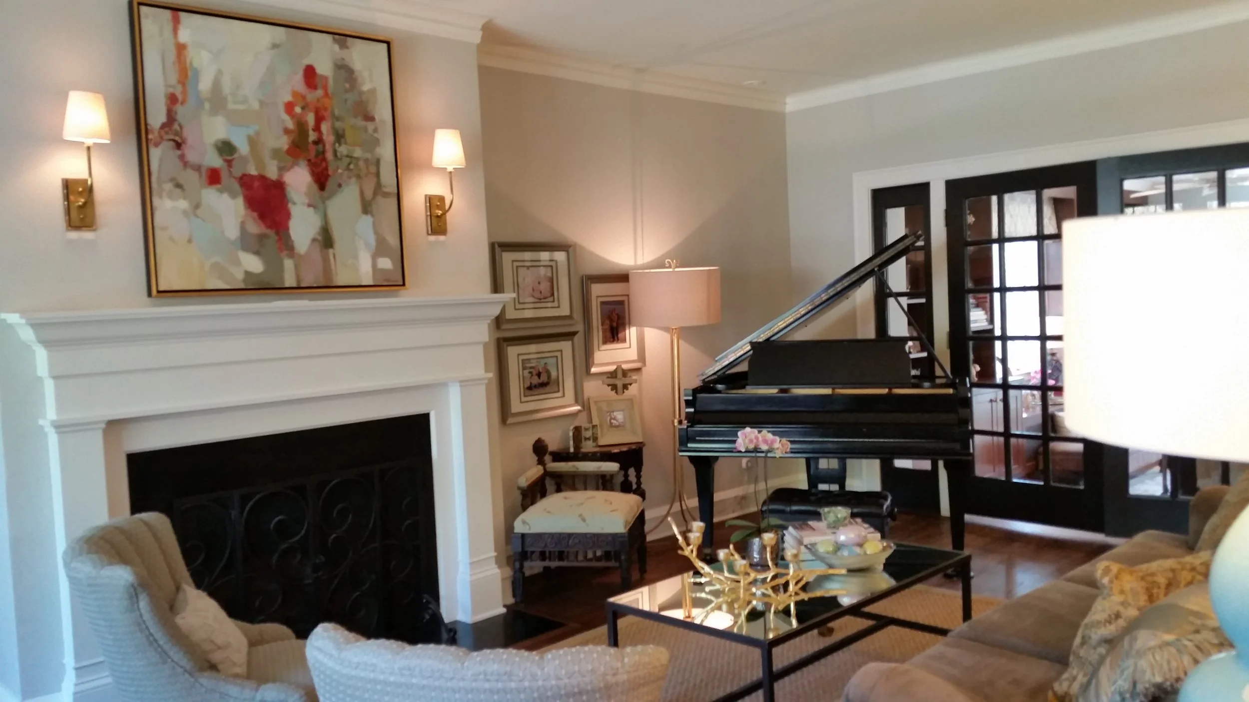 Family portraits grouped together with antique chair & floorlamp create a cozy spot next to the piano.